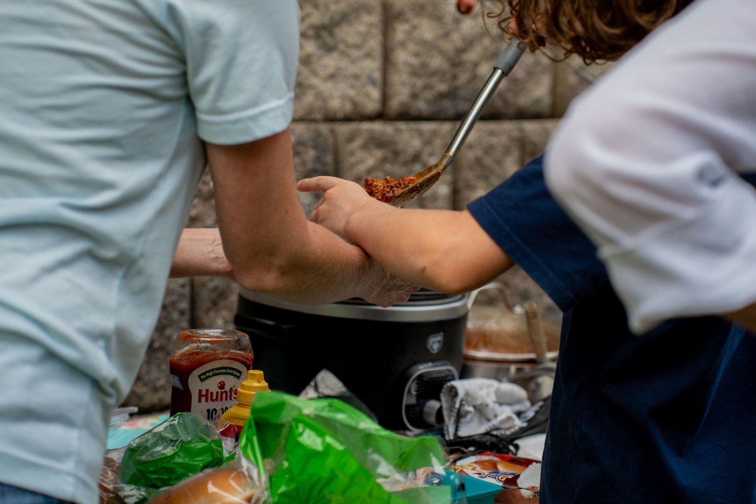 Close up of Woman and boy serving themselves chilli  outside