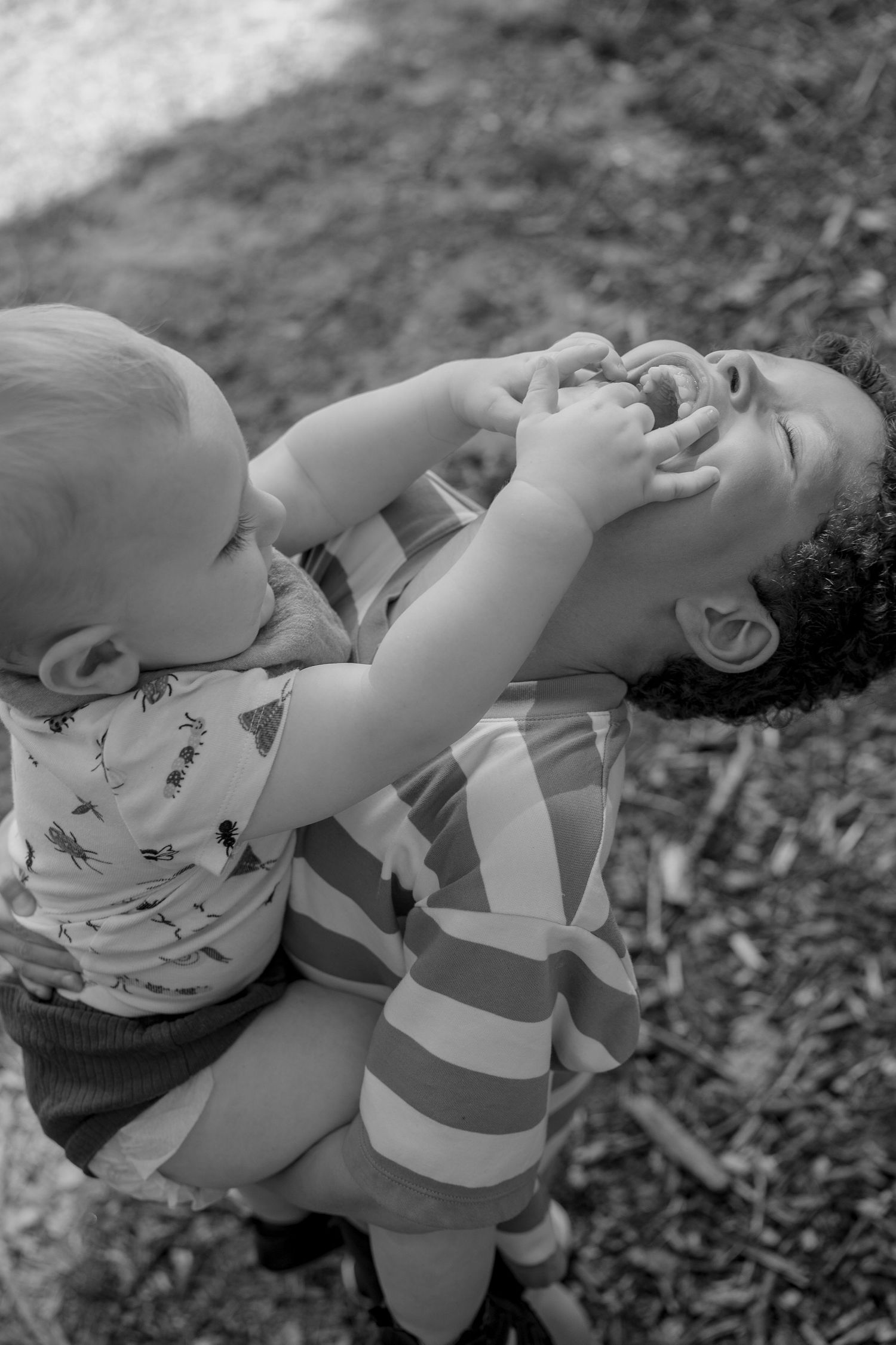 Toddler holding child's mouth while they laugh
