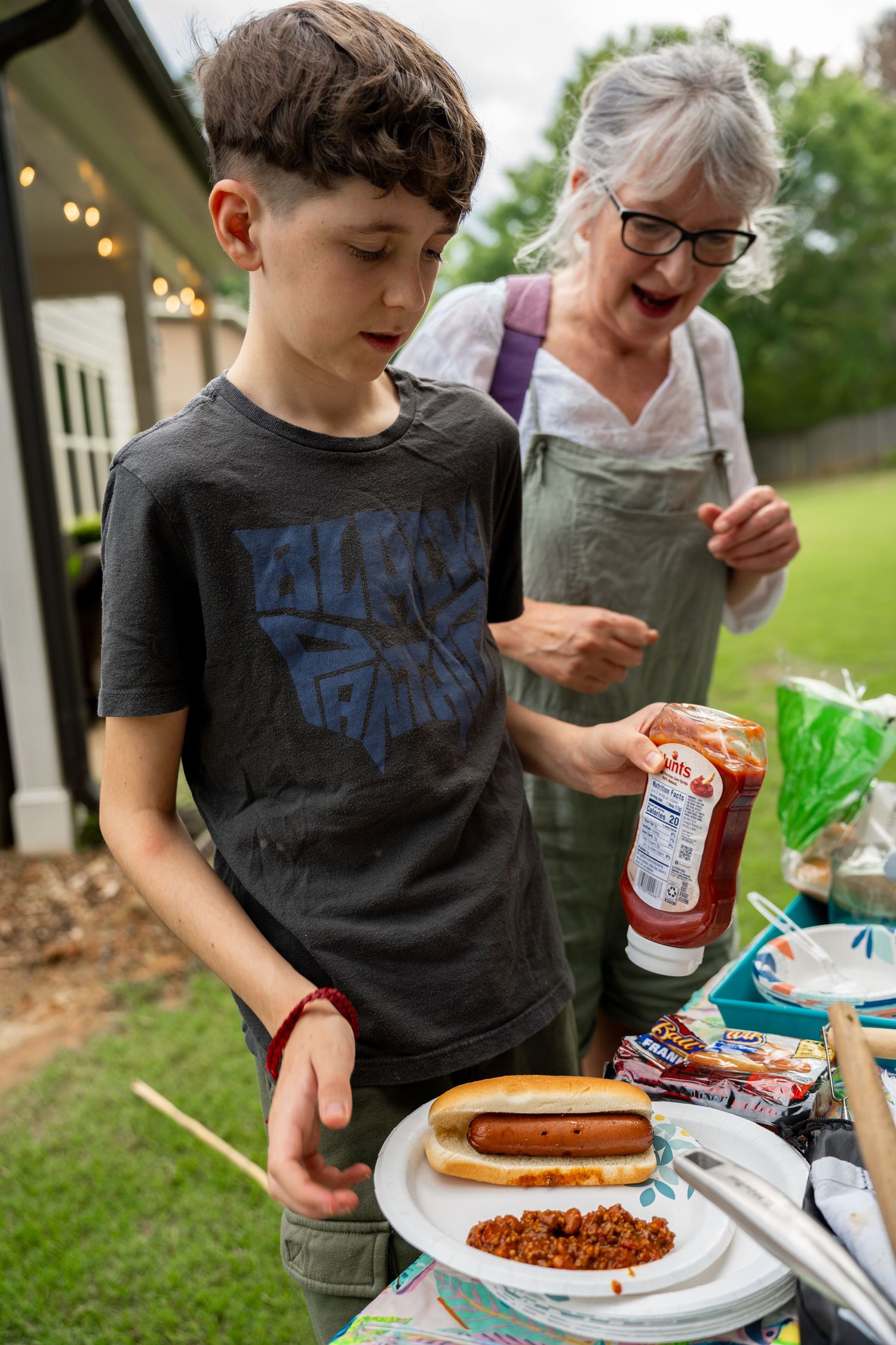 Woman and boy serving themselves hotdogs outside