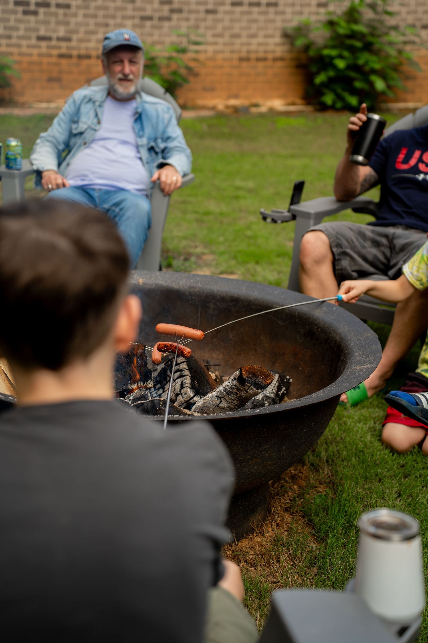 Group cooking hot dogs over fire