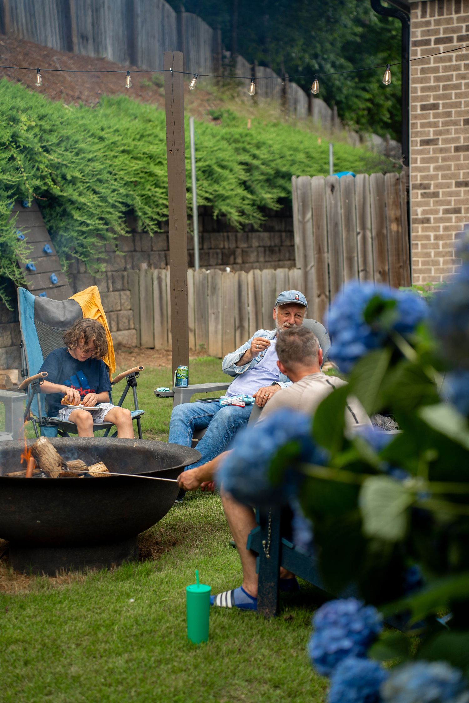 Group sitting round fire taken from behind flowers