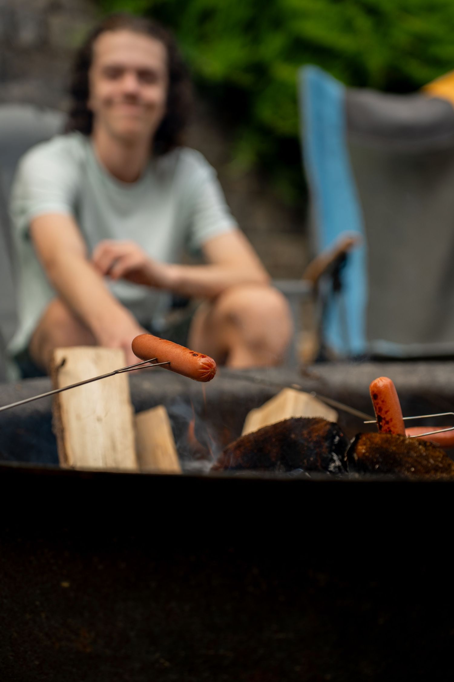 Child cooking hotdogs over fire