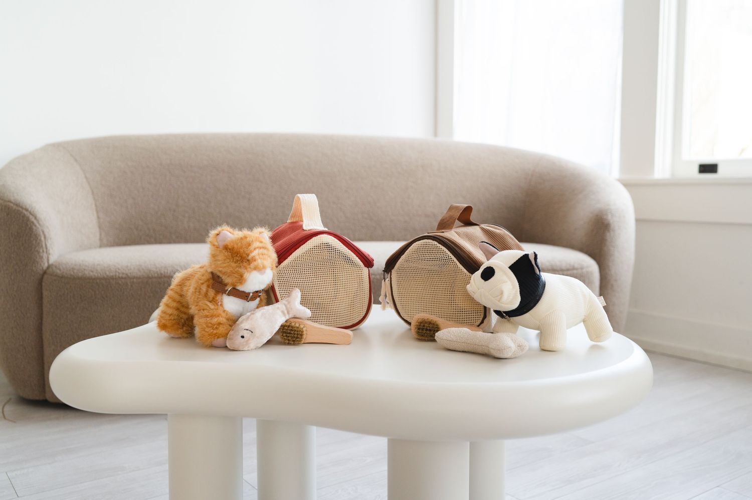 Plush cat and dog stuffed animals displayed with a wooden house on a white table.