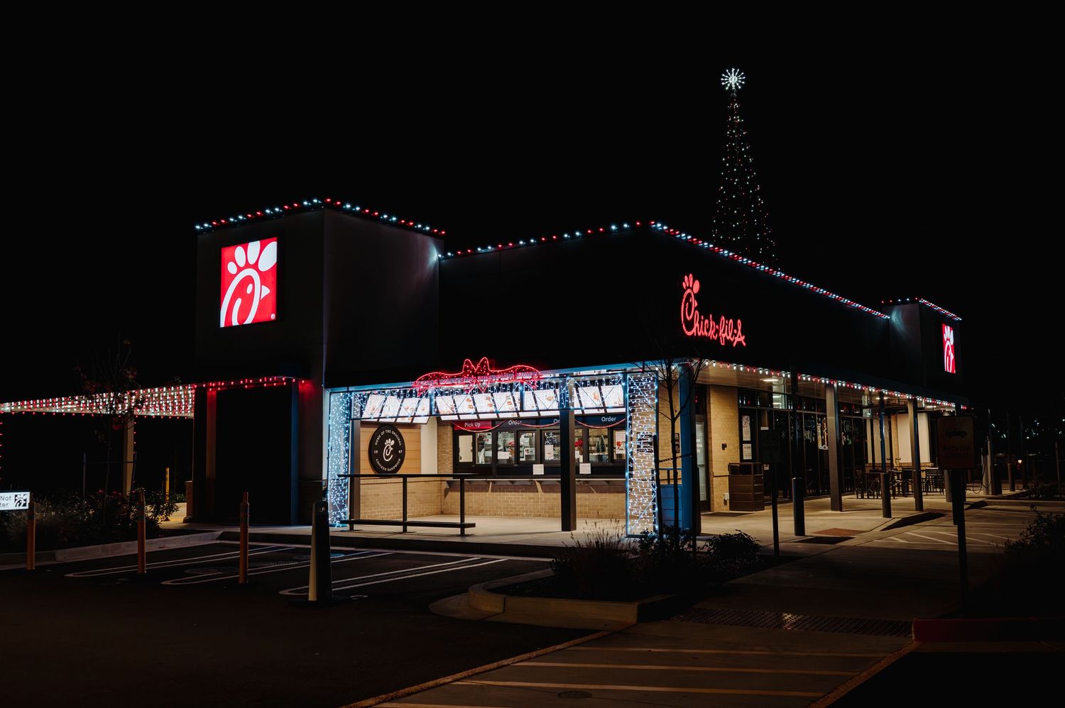 Chick-fil-A restaurant decorated with festive Christmas lights and holiday decor glowing at night.