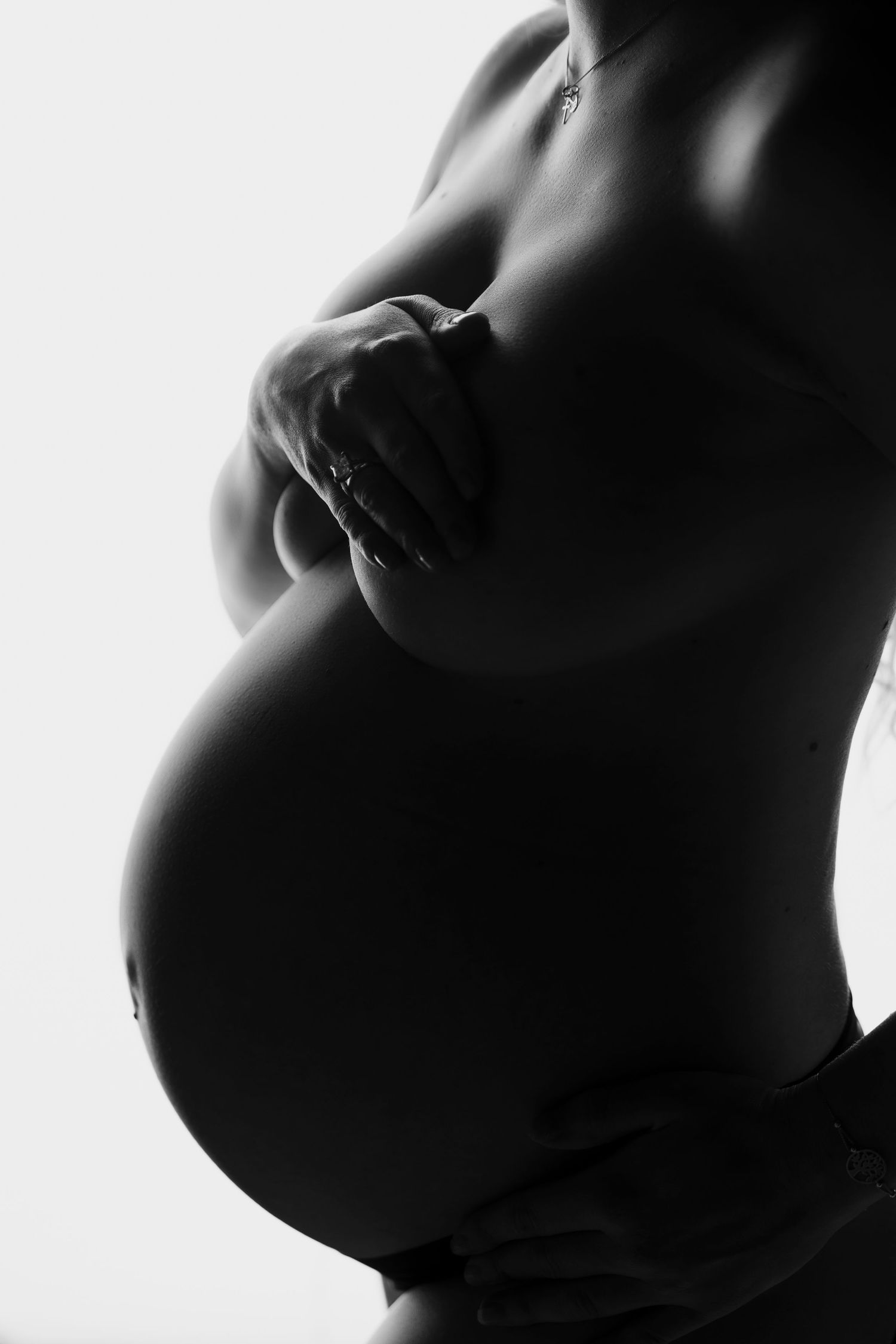 Dramatic side-lit maternity silhouettes showing the curves of pregnancy.