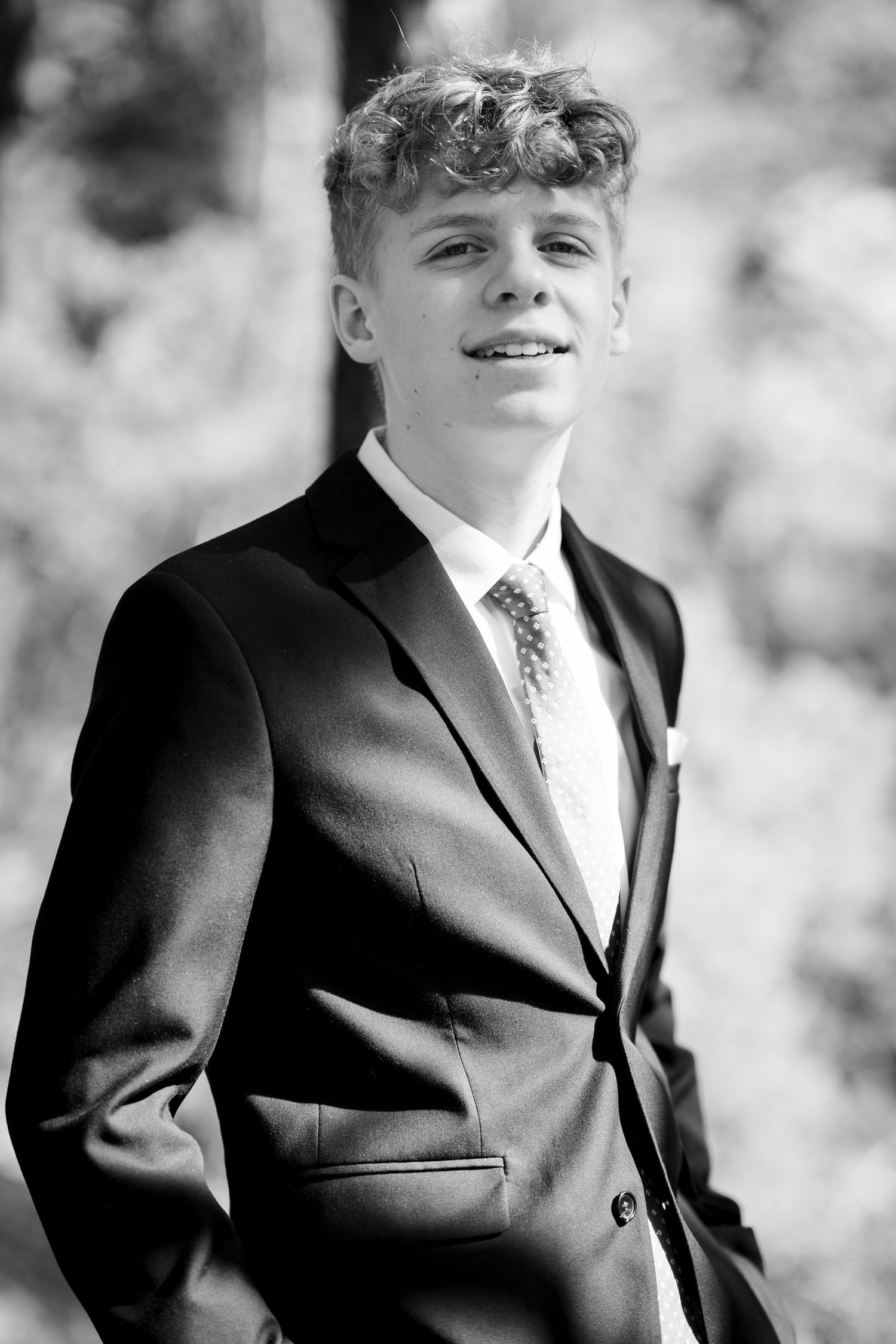 A formal portrait series showing different angles of a young person in a black suit and polka dot tie.