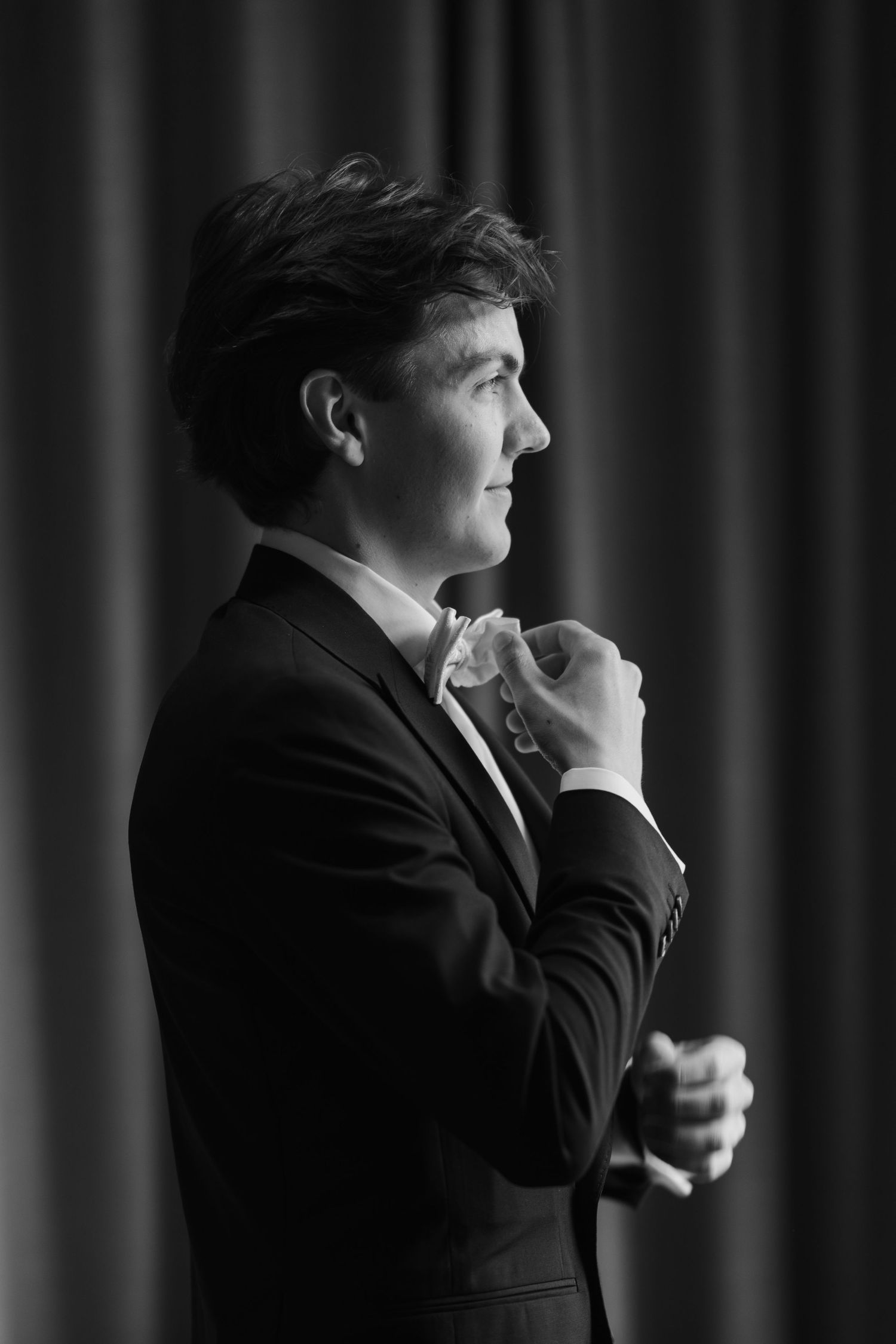 Dramatic black and white profile shots of a person in formal attire against a dark curtained background.