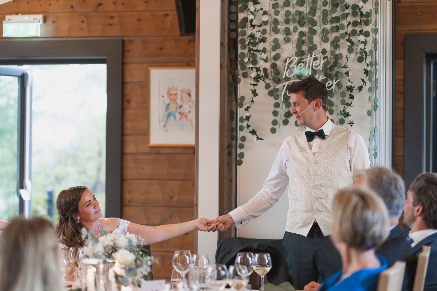 Wedding reception venue with wooden walls and hanging greenery decorations.