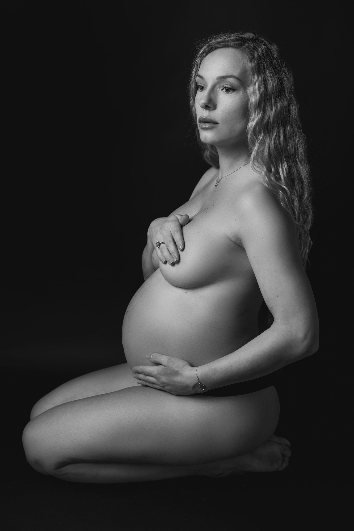 Dramatic black and white maternity boudoir photography with artistic pose.