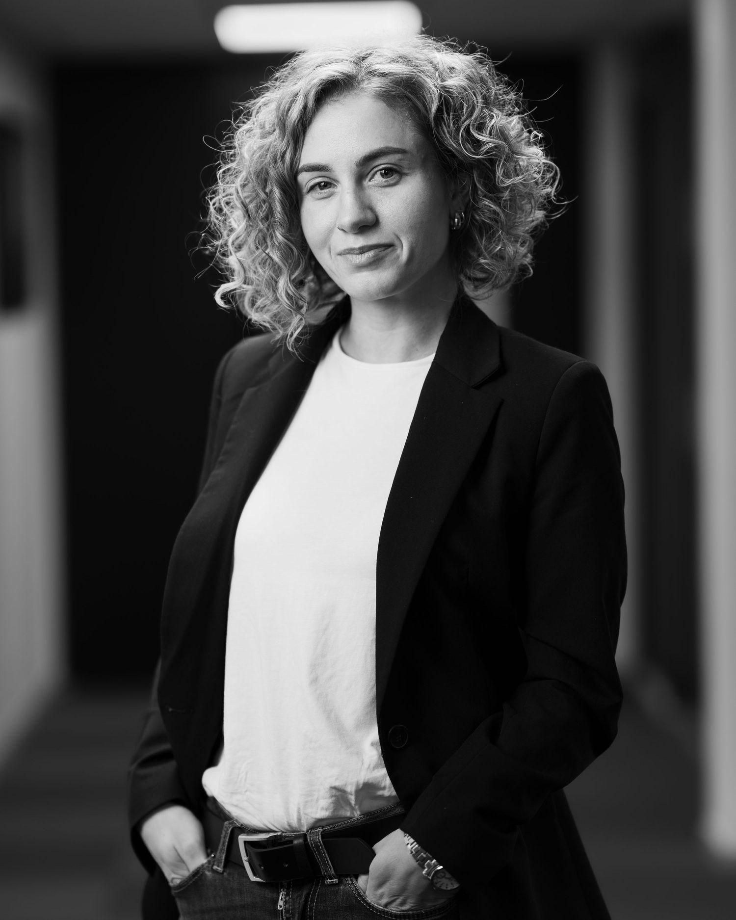 Professional black and white portrait of someone wearing a blazer in a minimalist setting.