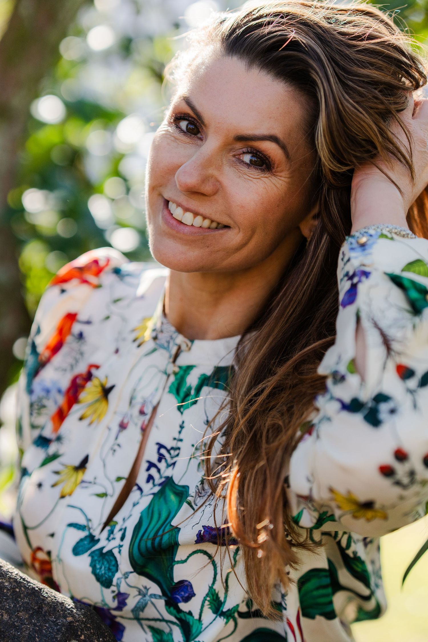 A colorful paint-splattered white sweater photographed in natural outdoor lighting.