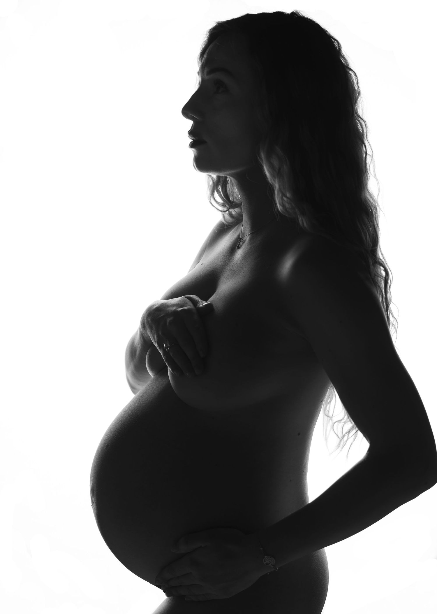 Artistic silhouette series showing pregnancy profile against white background.
