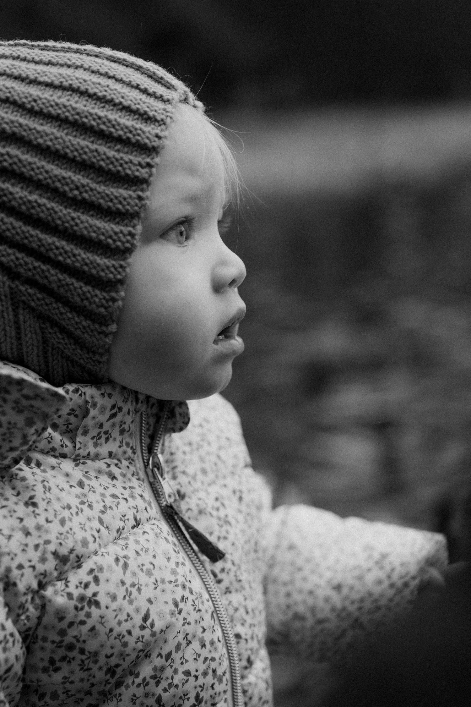 Black and white profile view of a child wearing a knit hat and patterned coat.
