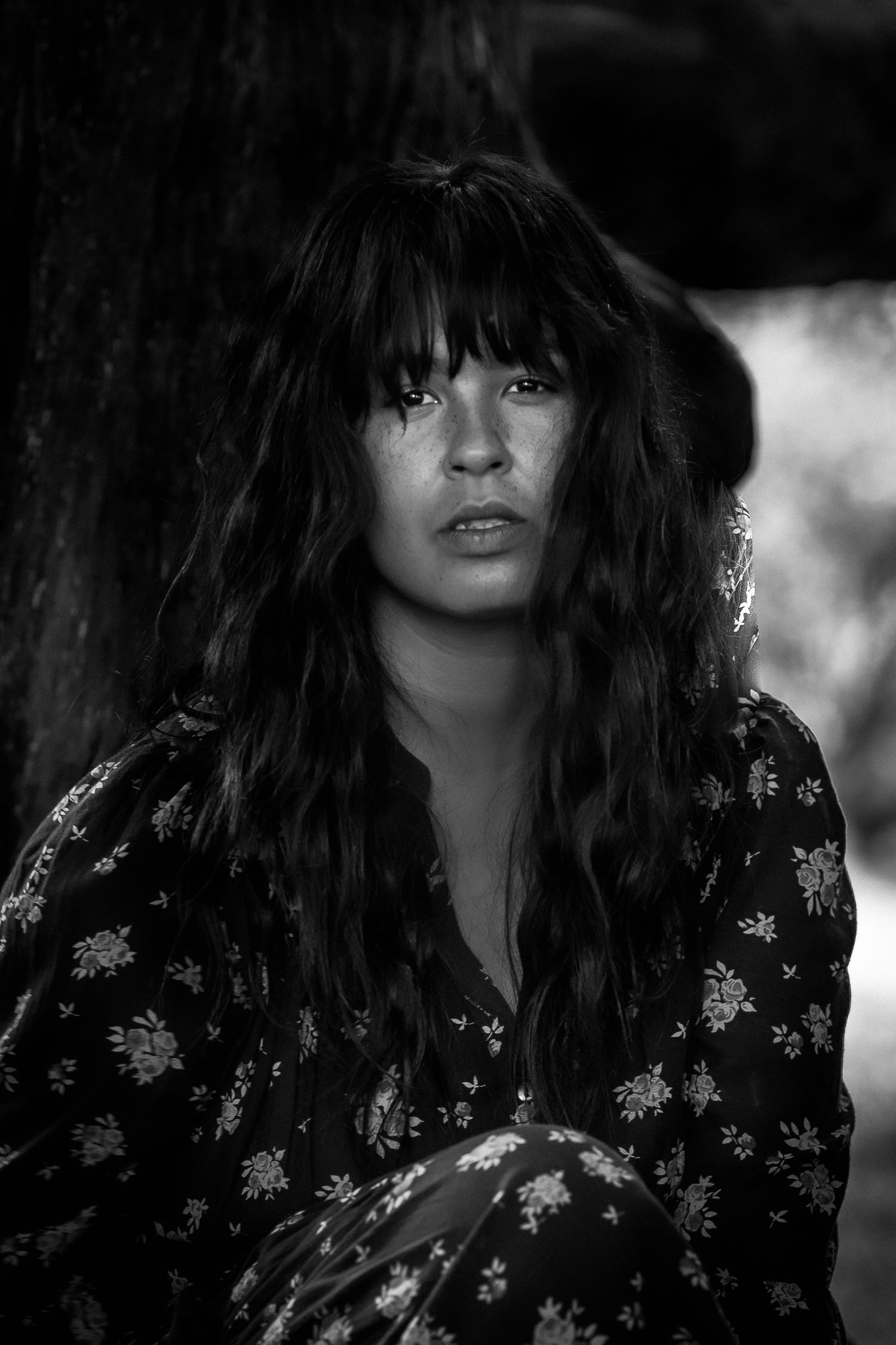 Artistic black and white portrait series featuring dark hair and floral print clothing against a moody background.