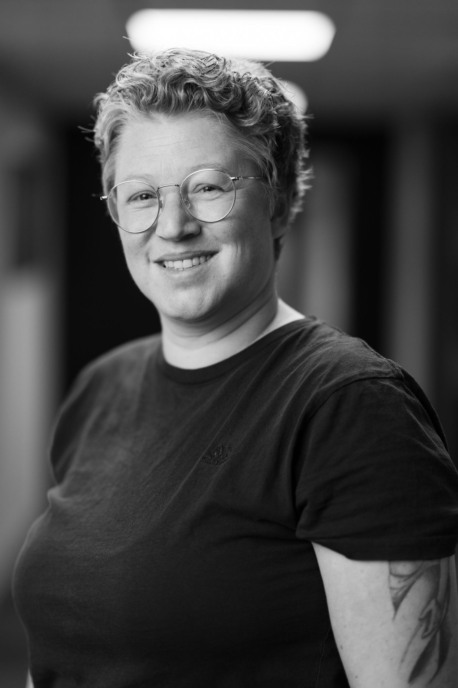 Black and white headshot of person wearing glasses and dark clothing.