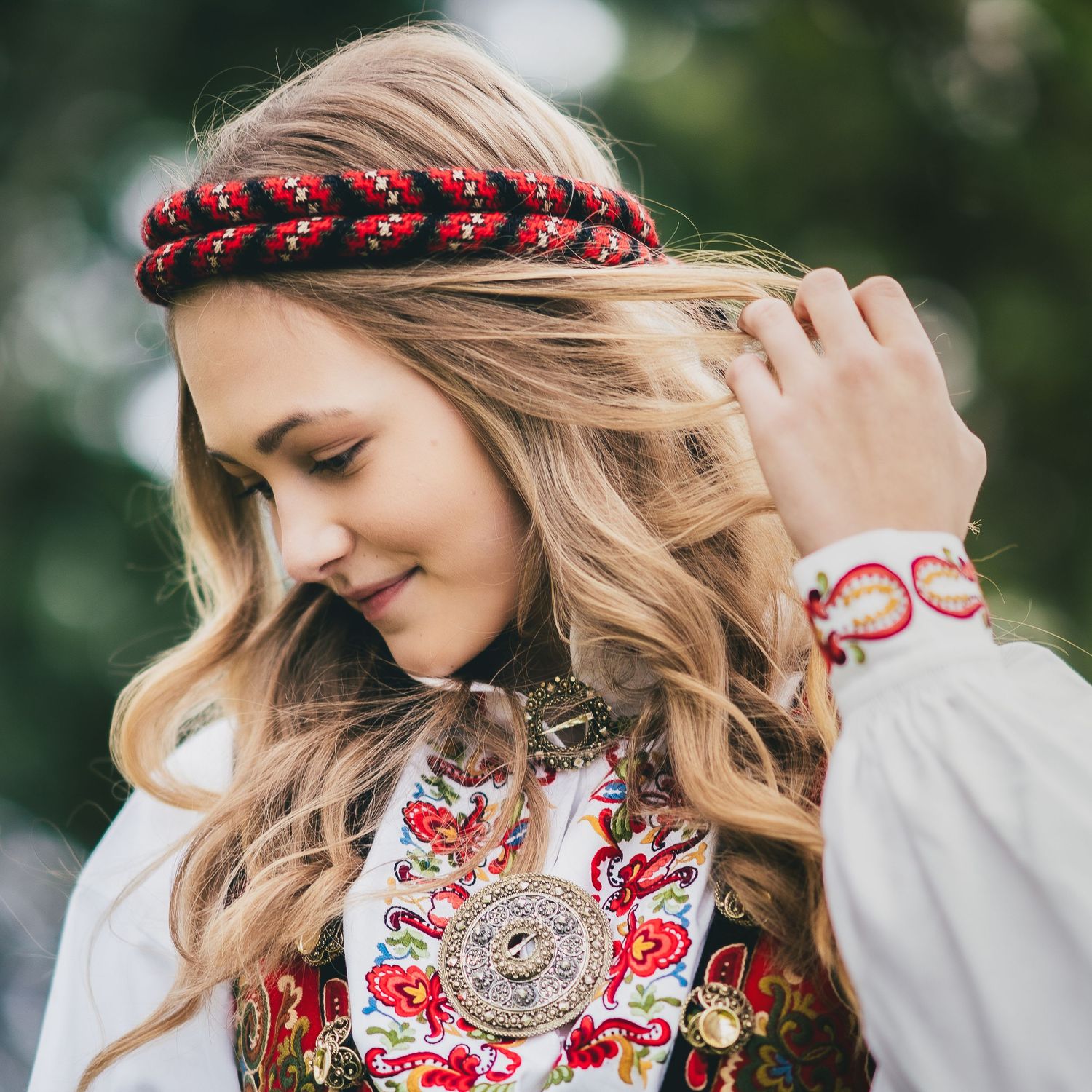 Floral embroidered white blouse with red flower crown accessory photographed outdoors.