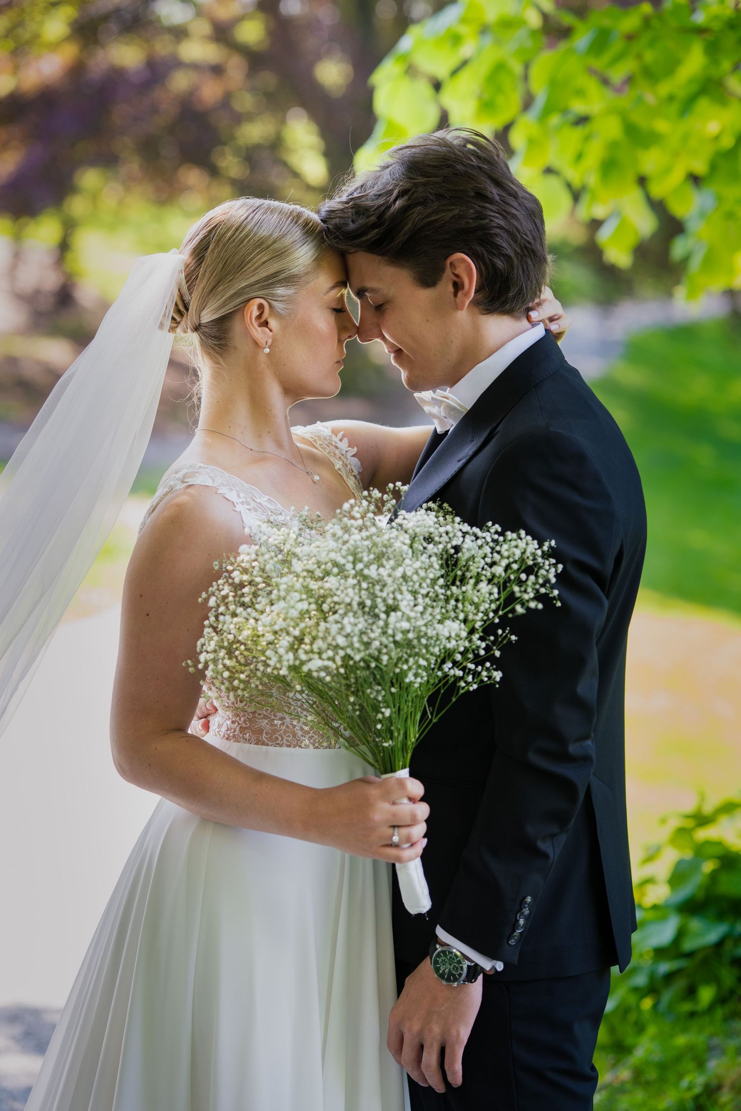 A romantic moment between newlyweds with baby's breath bouquet in a garden setting.