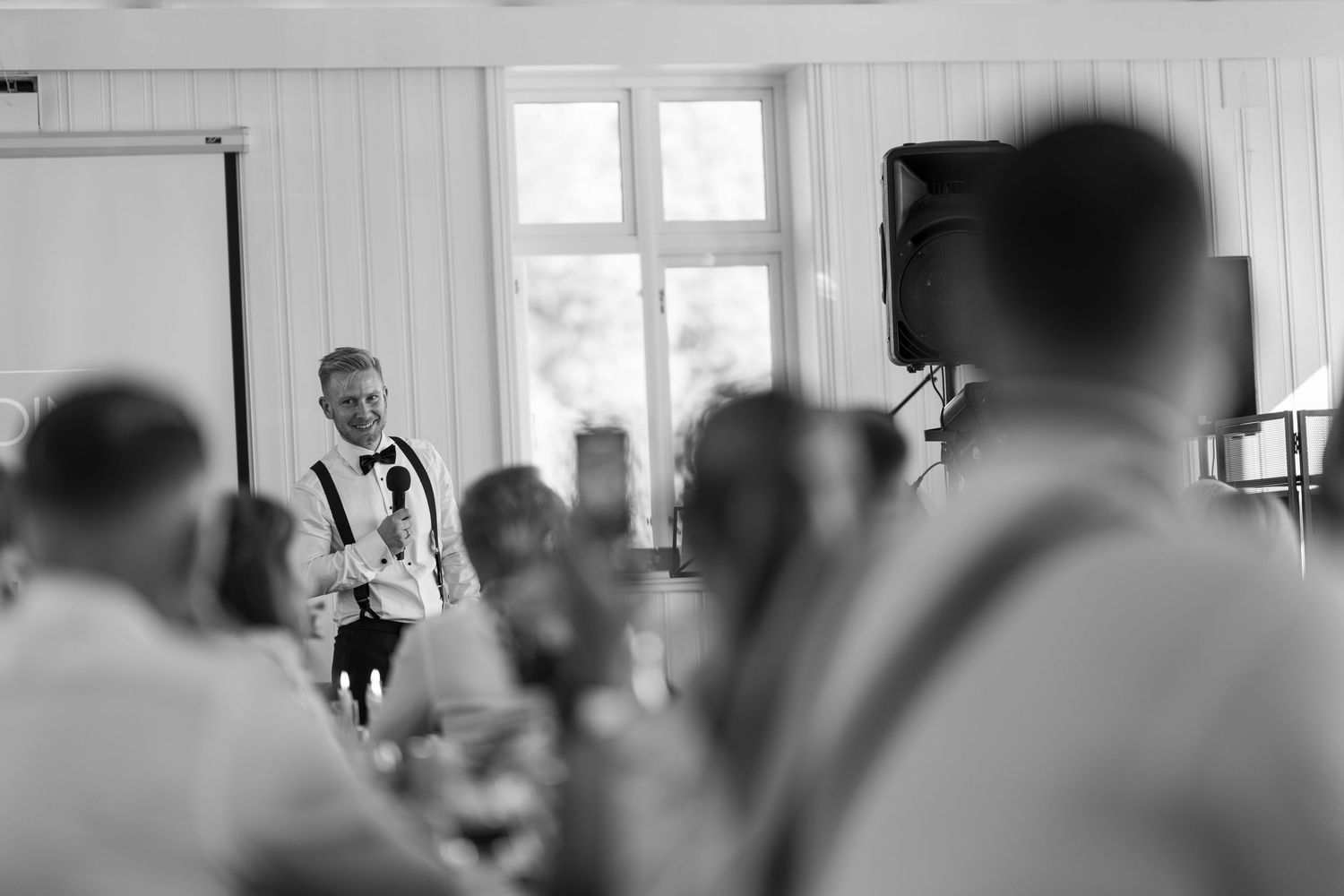 Black and white photo of wedding reception guests in conversation.