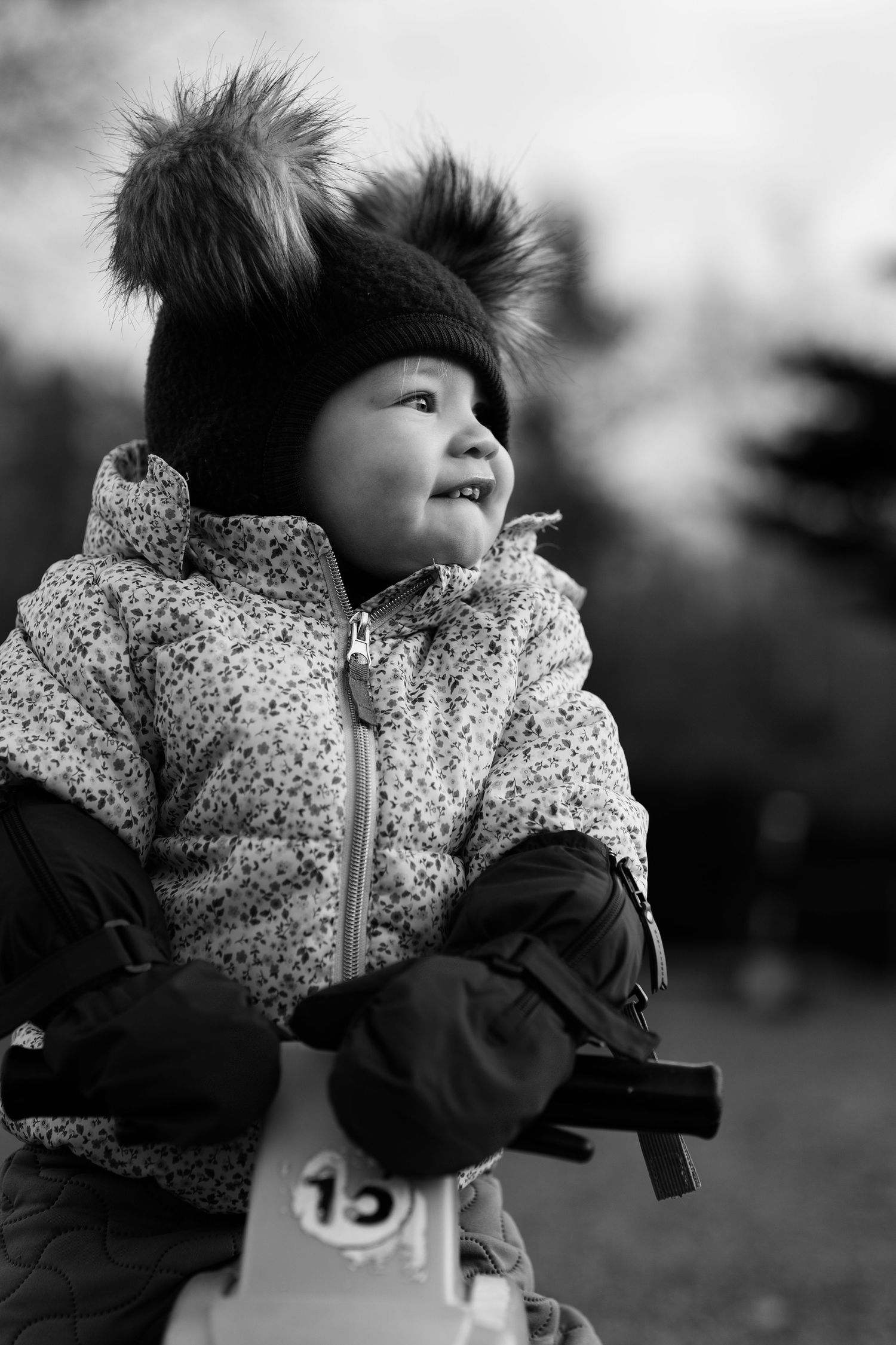 Black and white candid shot of a child in a patterned winter coat.