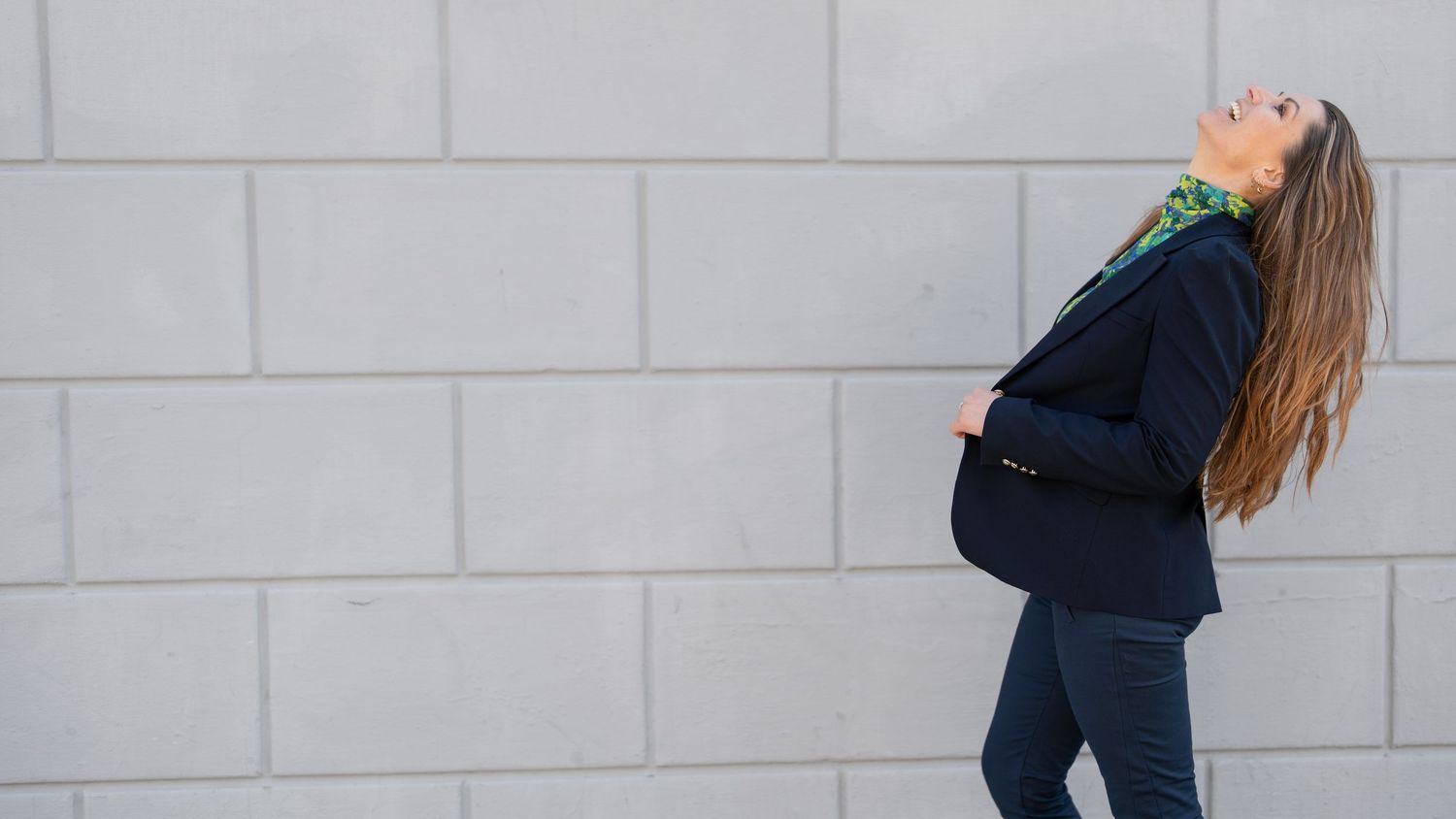 Figure in dark clothing walking against a light concrete wall background.