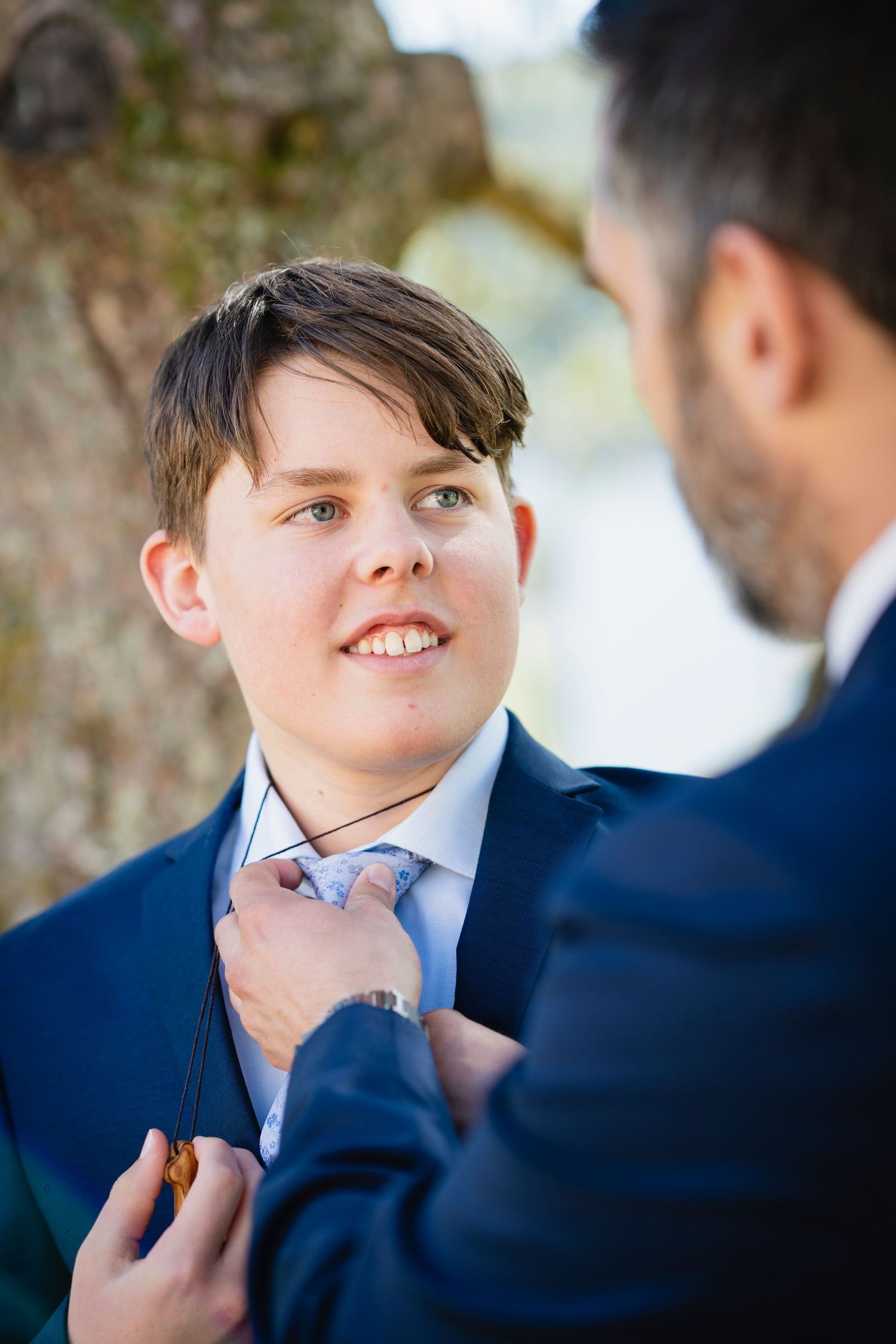 Close-up shots of someone having their tie adjusted against a blurred background.