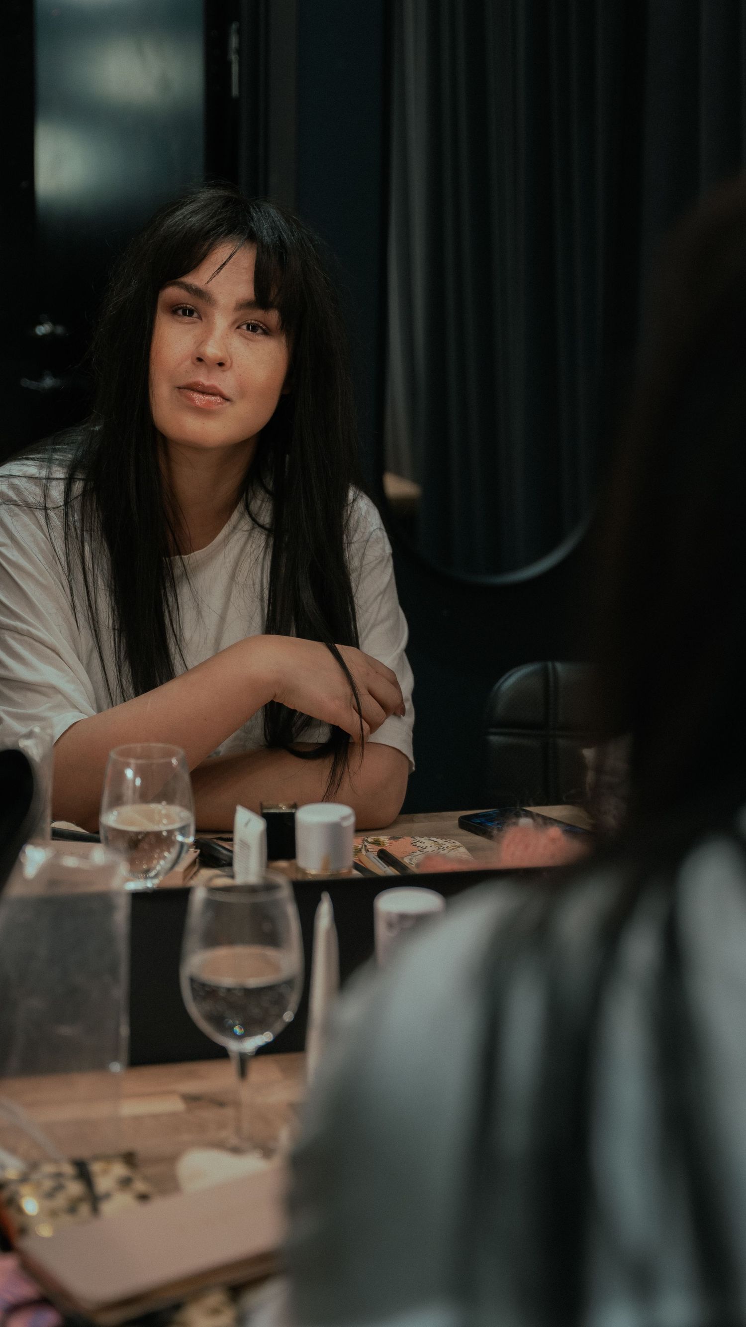 Moody restaurant scene with wine glasses and dark lighting.