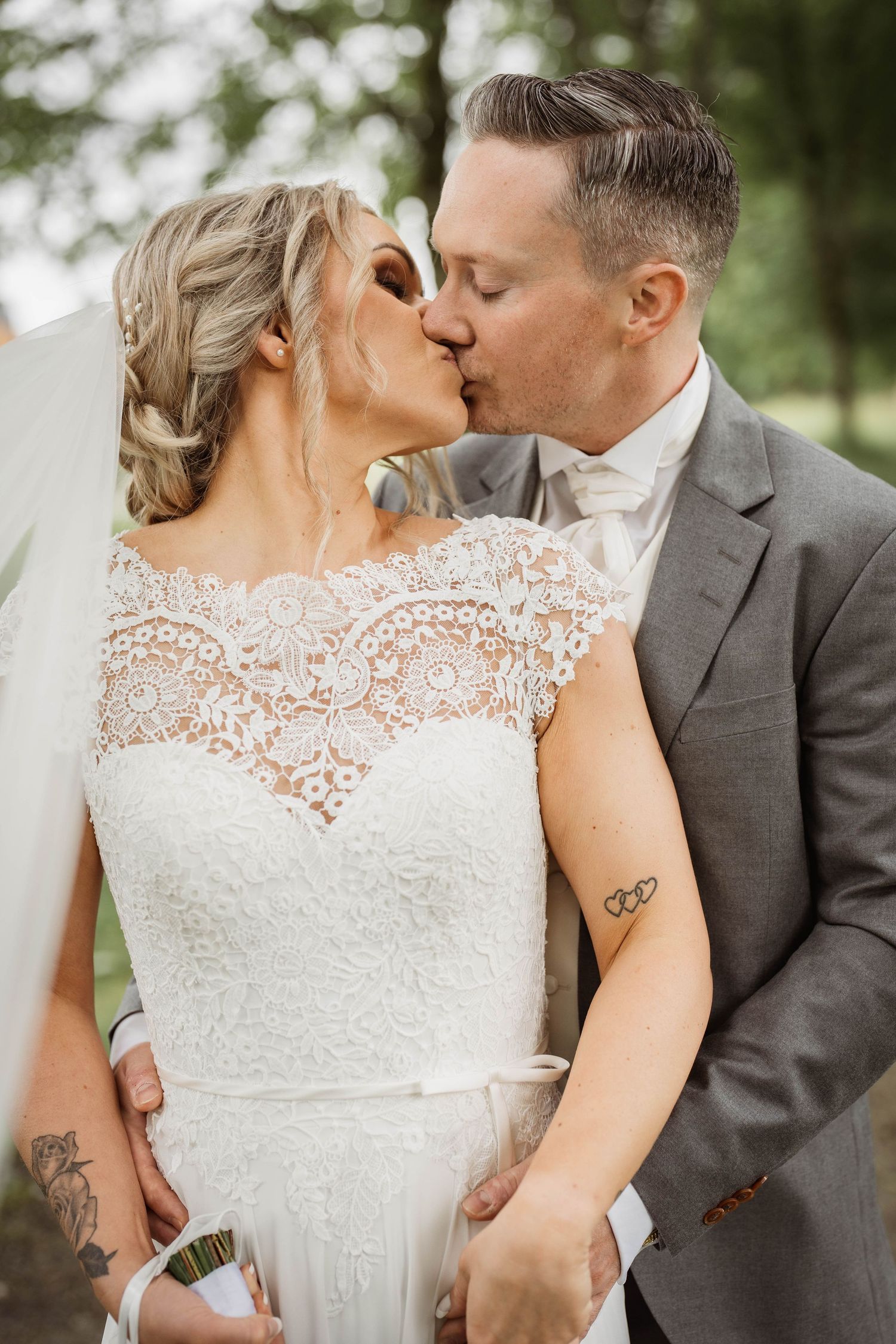 Close-up shots of newlyweds in lace wedding dress and grey suit sharing tender moments.