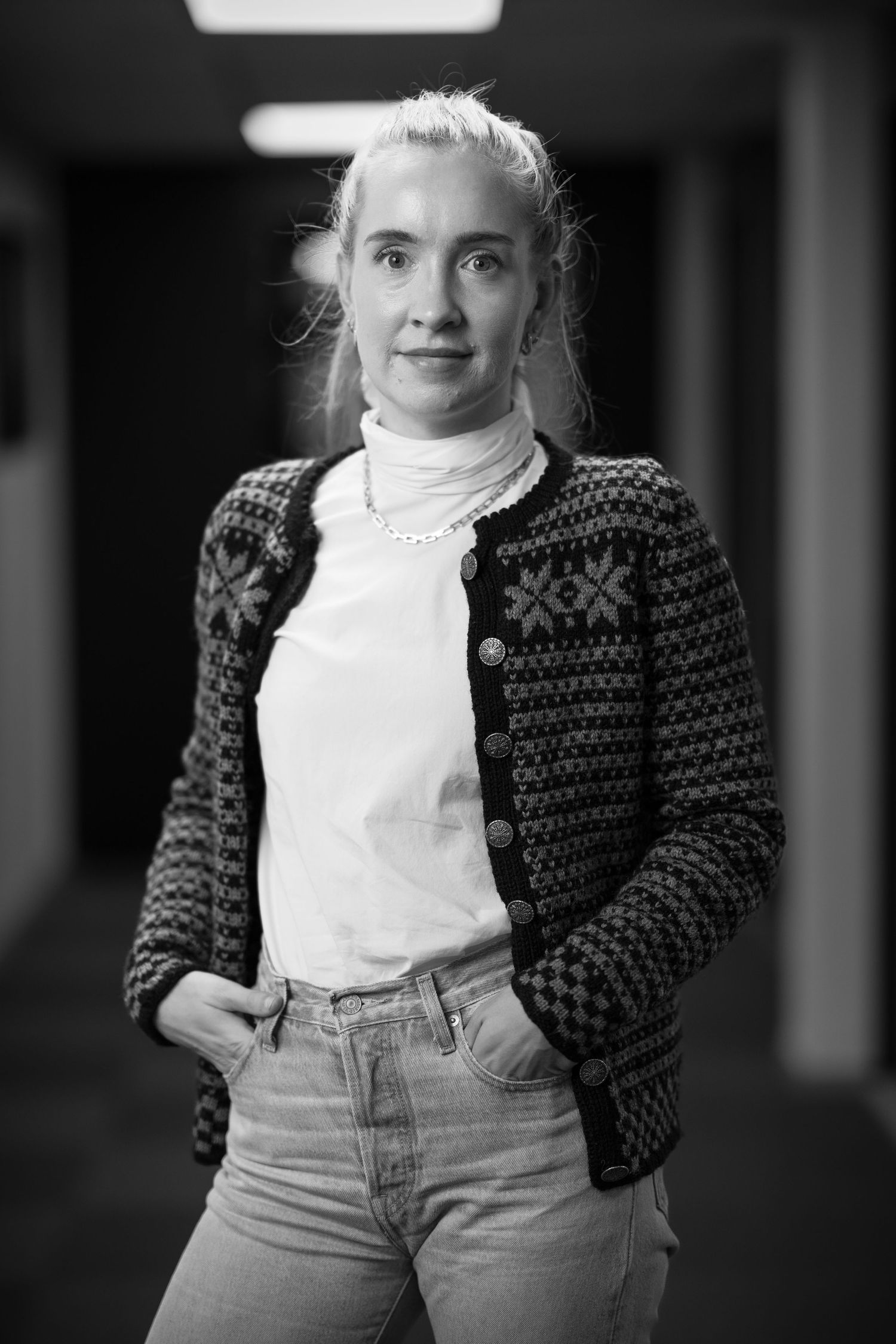 Black and white portrait of someone wearing patterned sweater and white collar shirt.