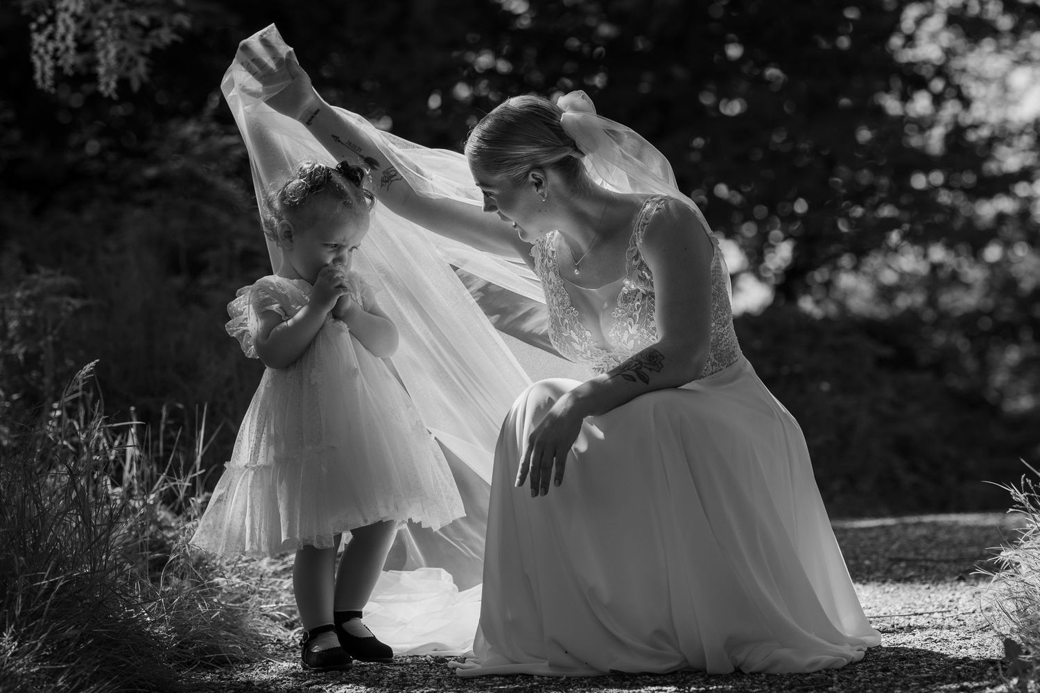 Romantic wedding couple poses on the ground in a natural outdoor setting.