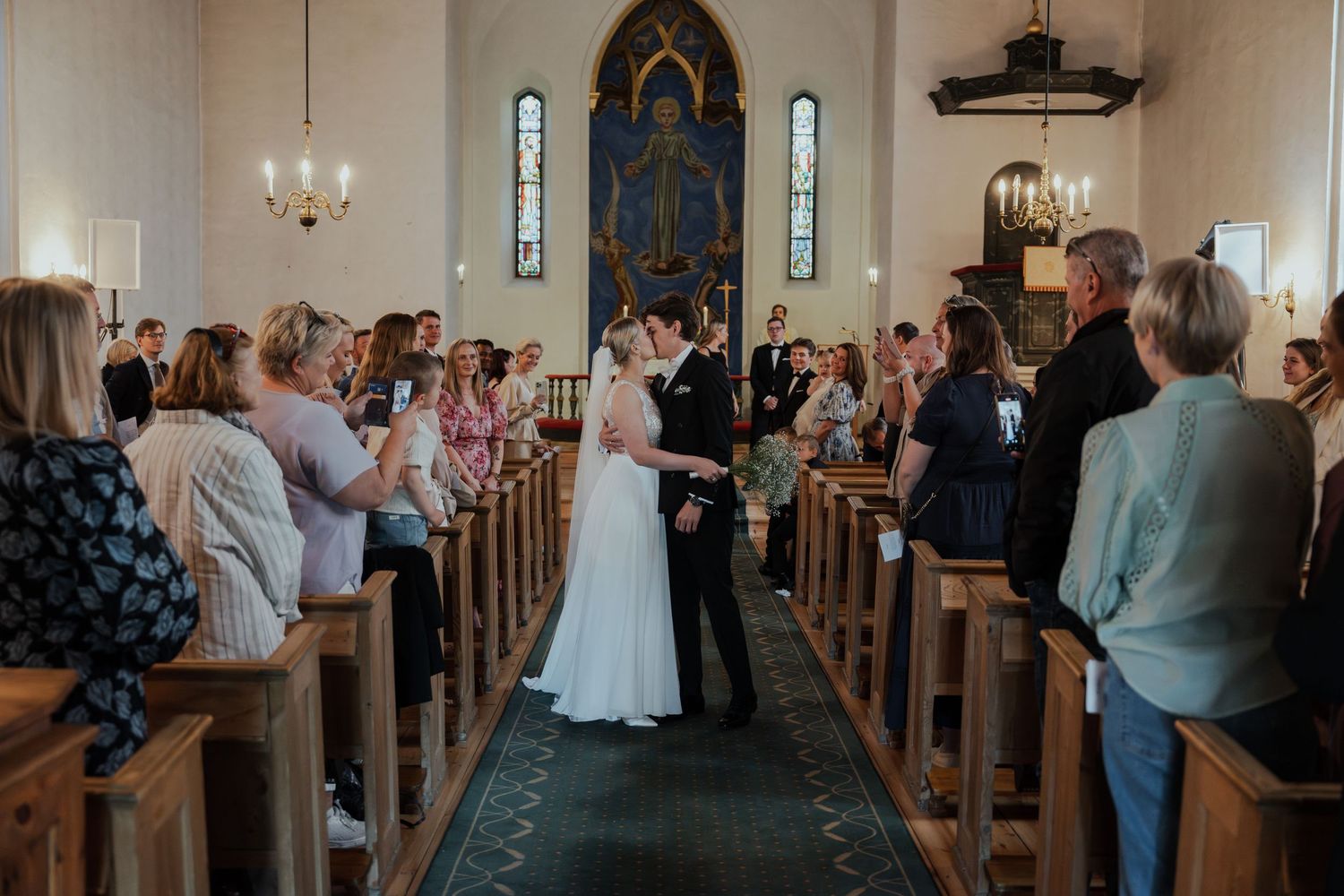 Interior of a traditional church during a wedding ceremony with guests seated in wooden pews.
