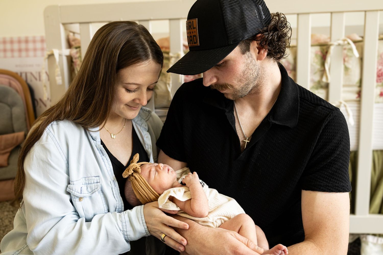 New parents tenderly hold their sleeping newborn baby in a nursery setting.