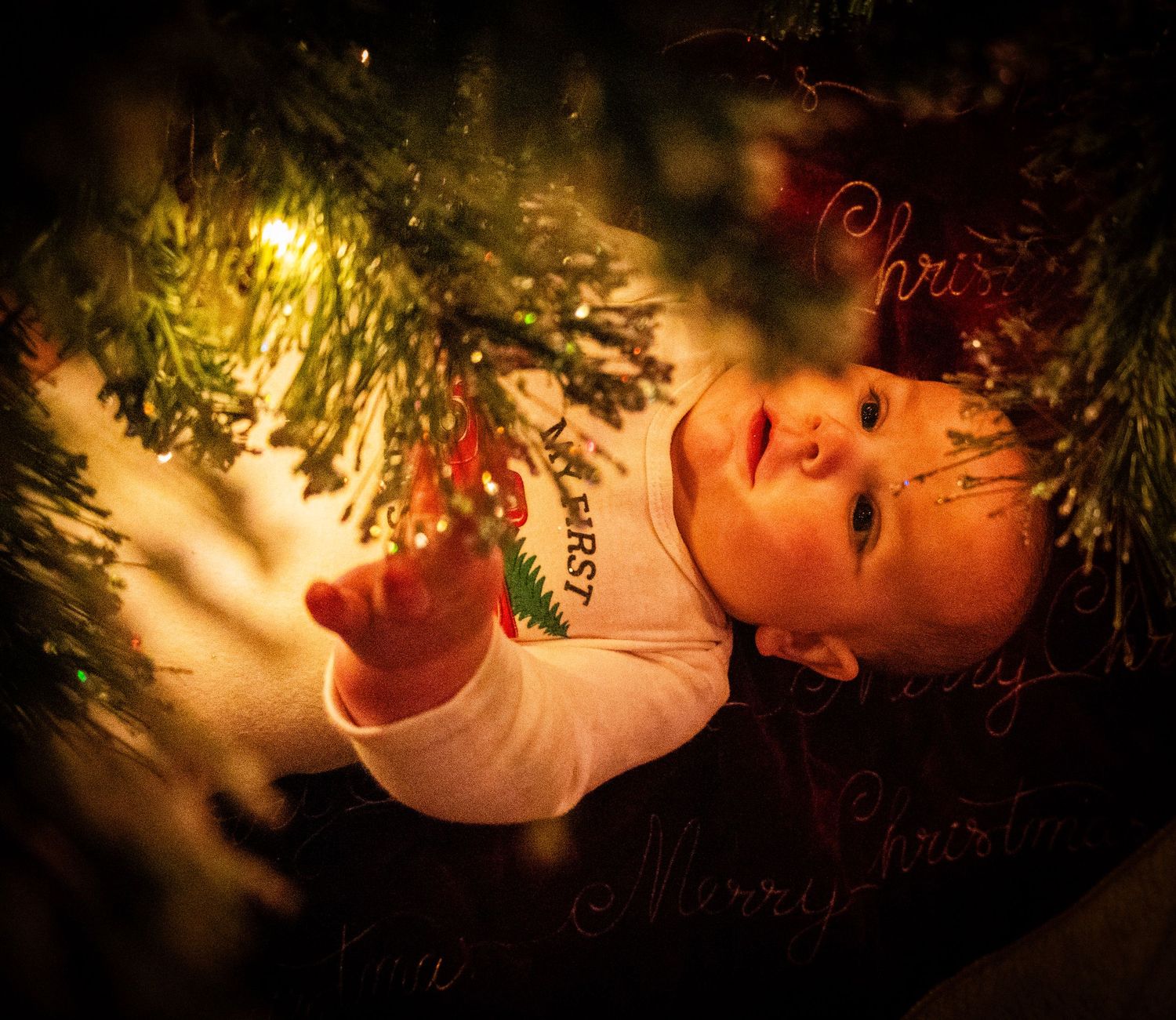 Close-up of glowing Christmas ornaments hanging on an evergreen tree.