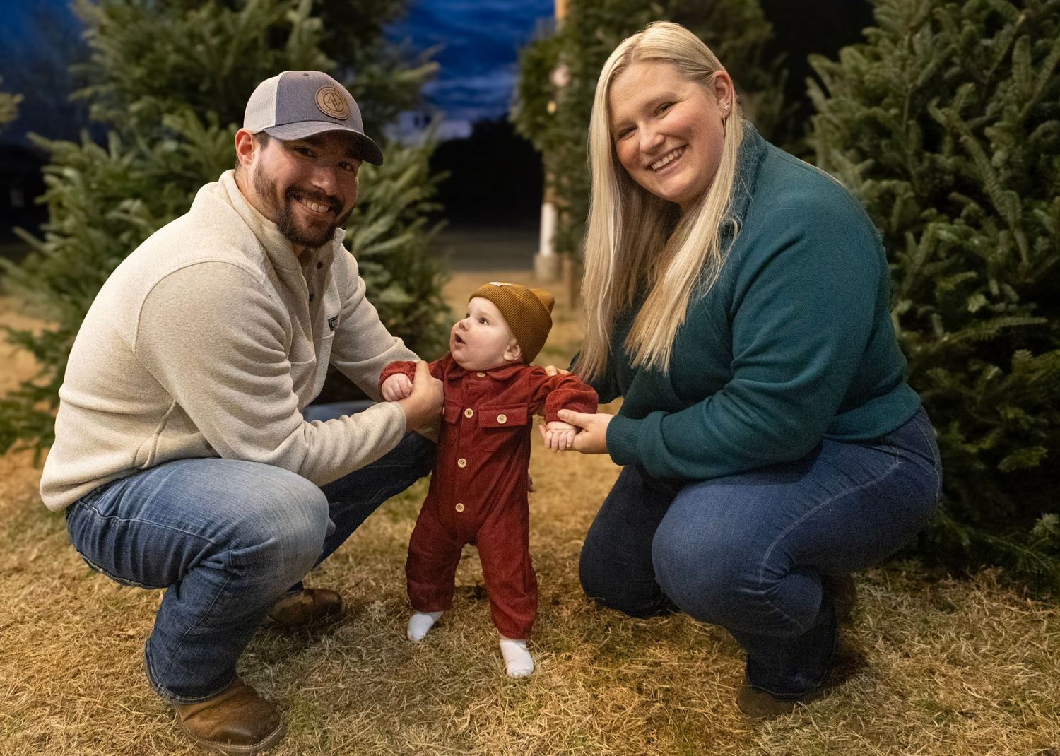 A family visits a Christmas tree farm together on a winter evening.