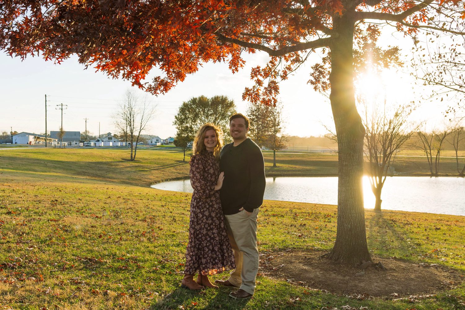 Autumn trees with golden sunlight streaming through orange leaves create a warm glow in a park setting.