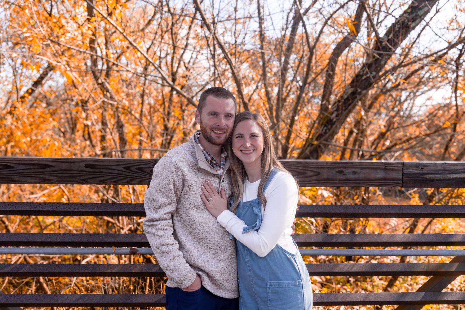A couple sharing intimate moments against an autumn backdrop with orange foliage.
