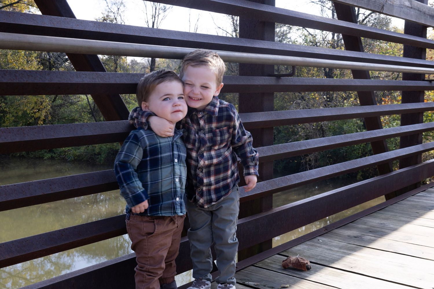 Children sitting together on wooden bridge in autumn setting.