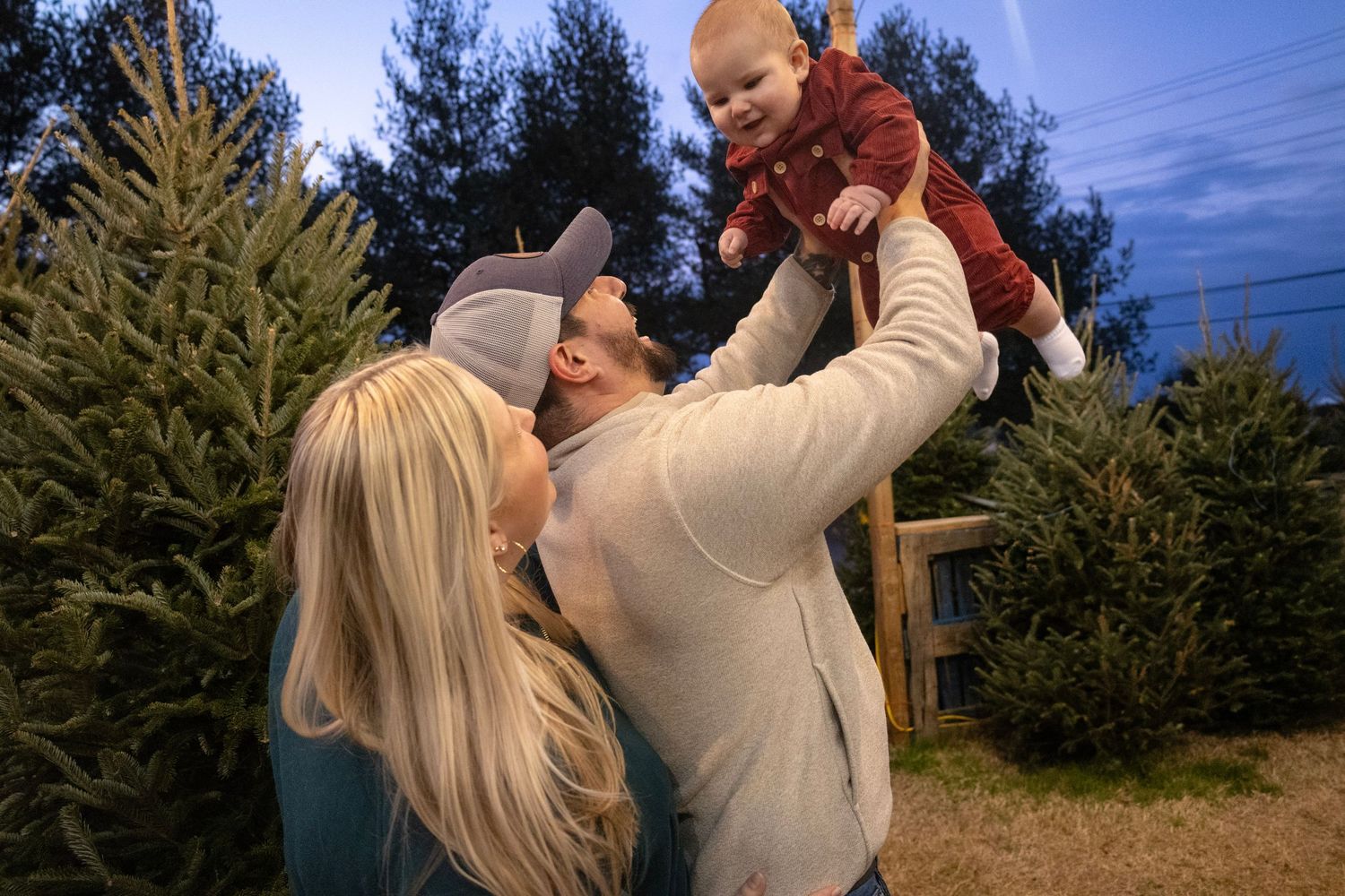 A joyful family moment at a Christmas tree farm during twilight.
