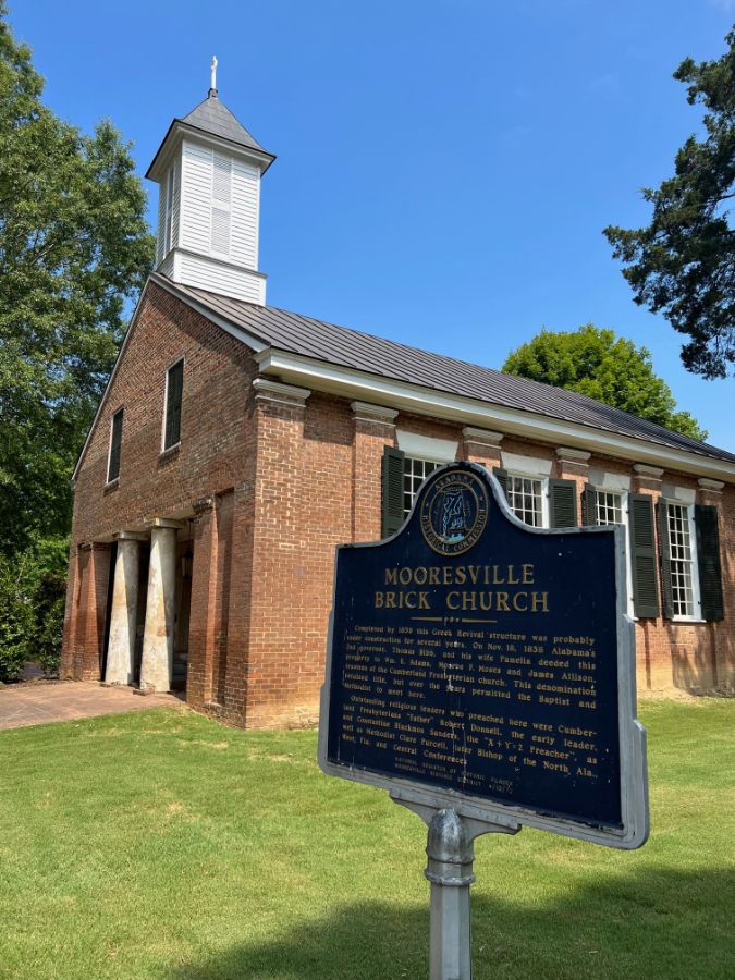 Historic Mooresville Brick Church red brick building with white steeple and commemorative marker on green lawn.