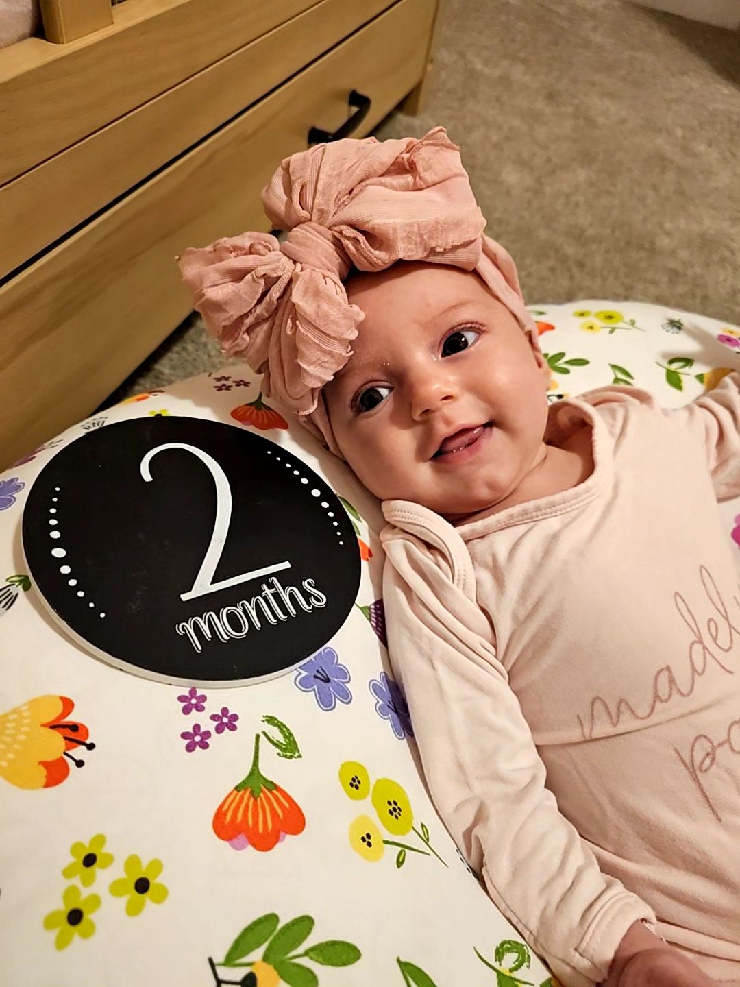 Baby in pink outfit with milestone markers showing growth progress.