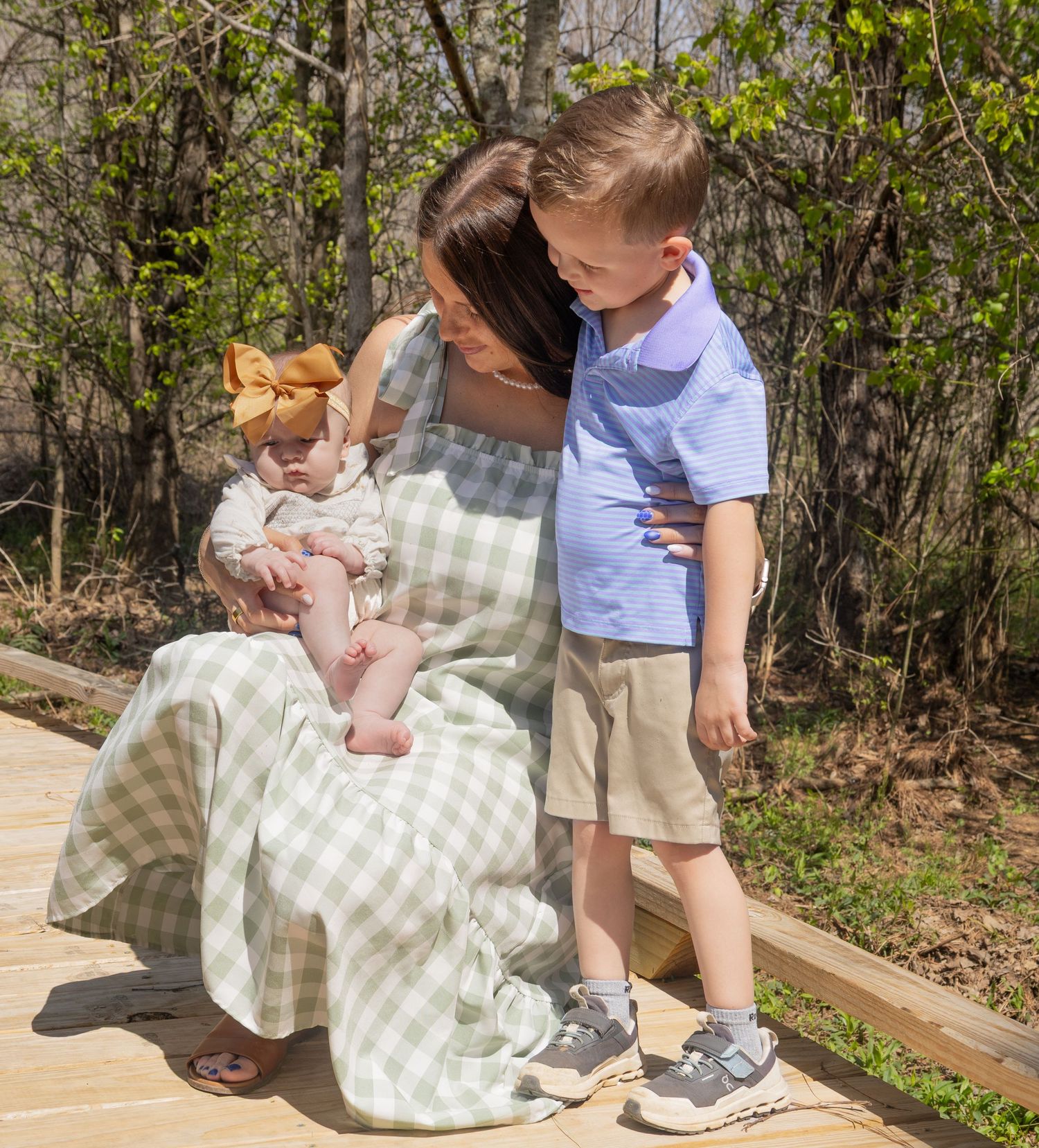 A parent and child sit together on a wooden bench in a garden setting while sharing a tender moment.