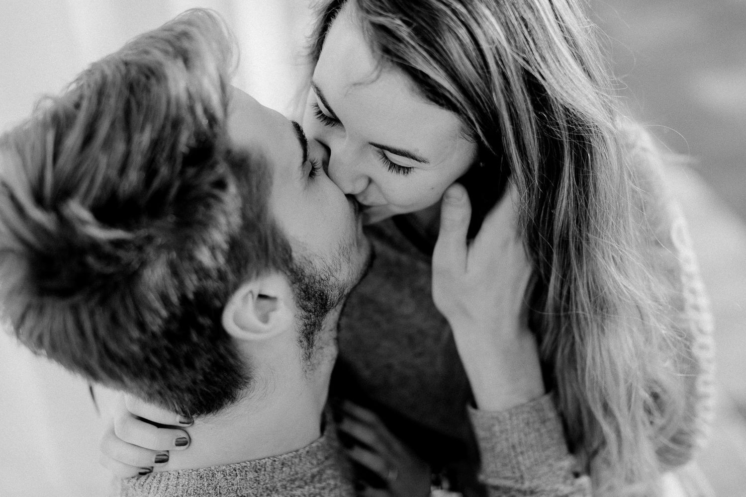 A couple sharing a tender kiss in a black and white close-up portrait.