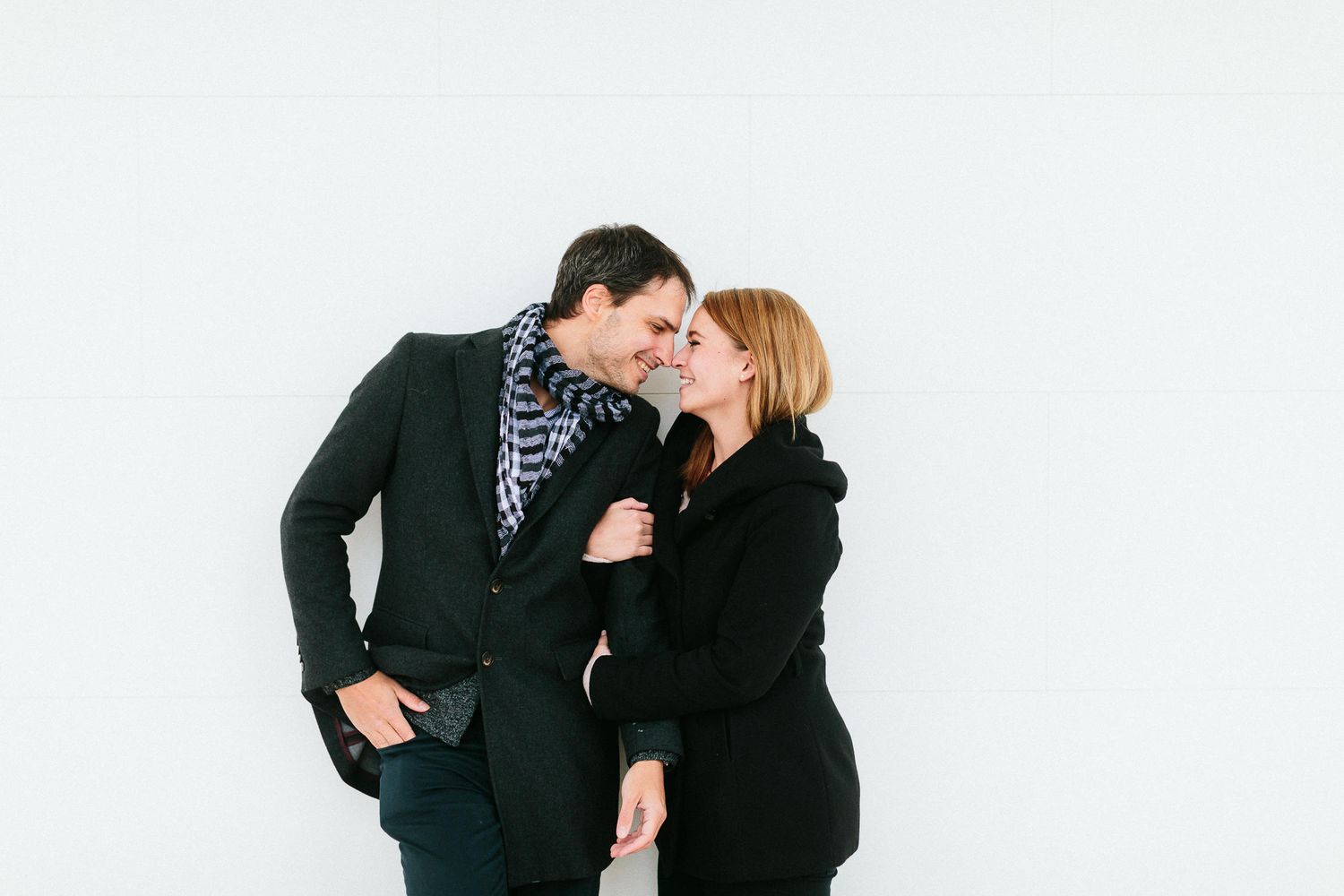 Stylish couple leaning in for a kiss against a clean white background.
