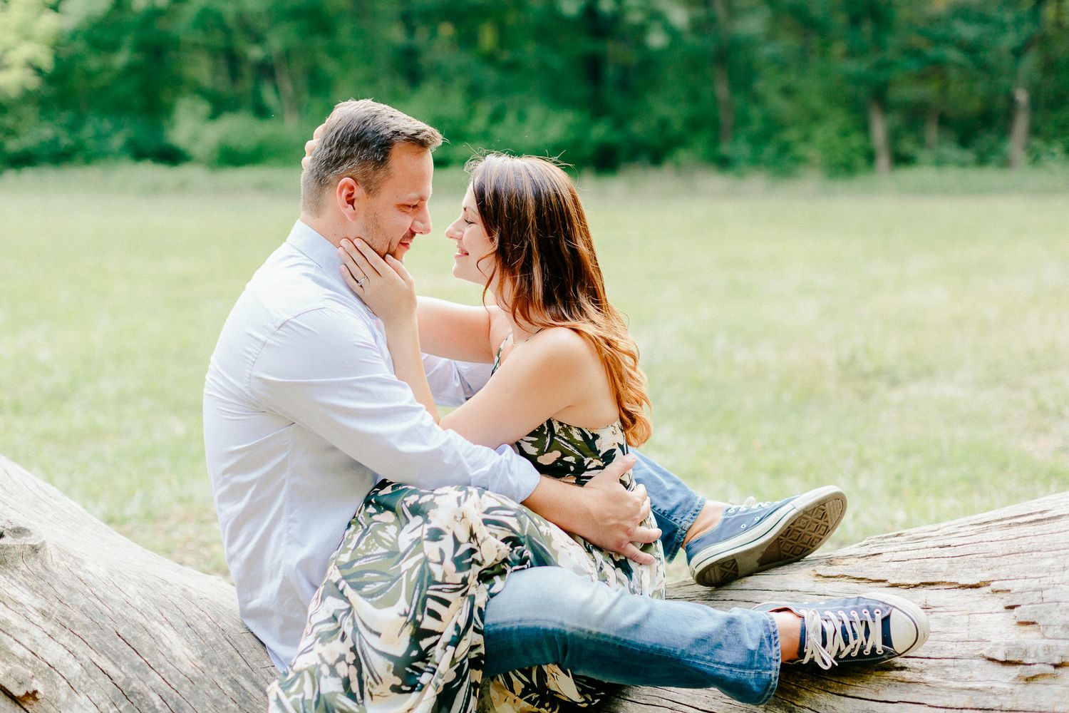 Couple sitting on a log in a park, gazing lovingly at each other.