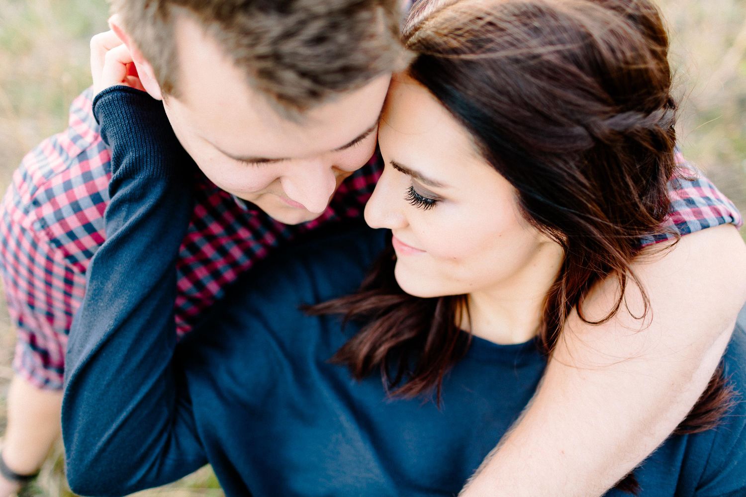Intimate close-up of a couple touching foreheads tenderly during an outdoor engagement photo session.