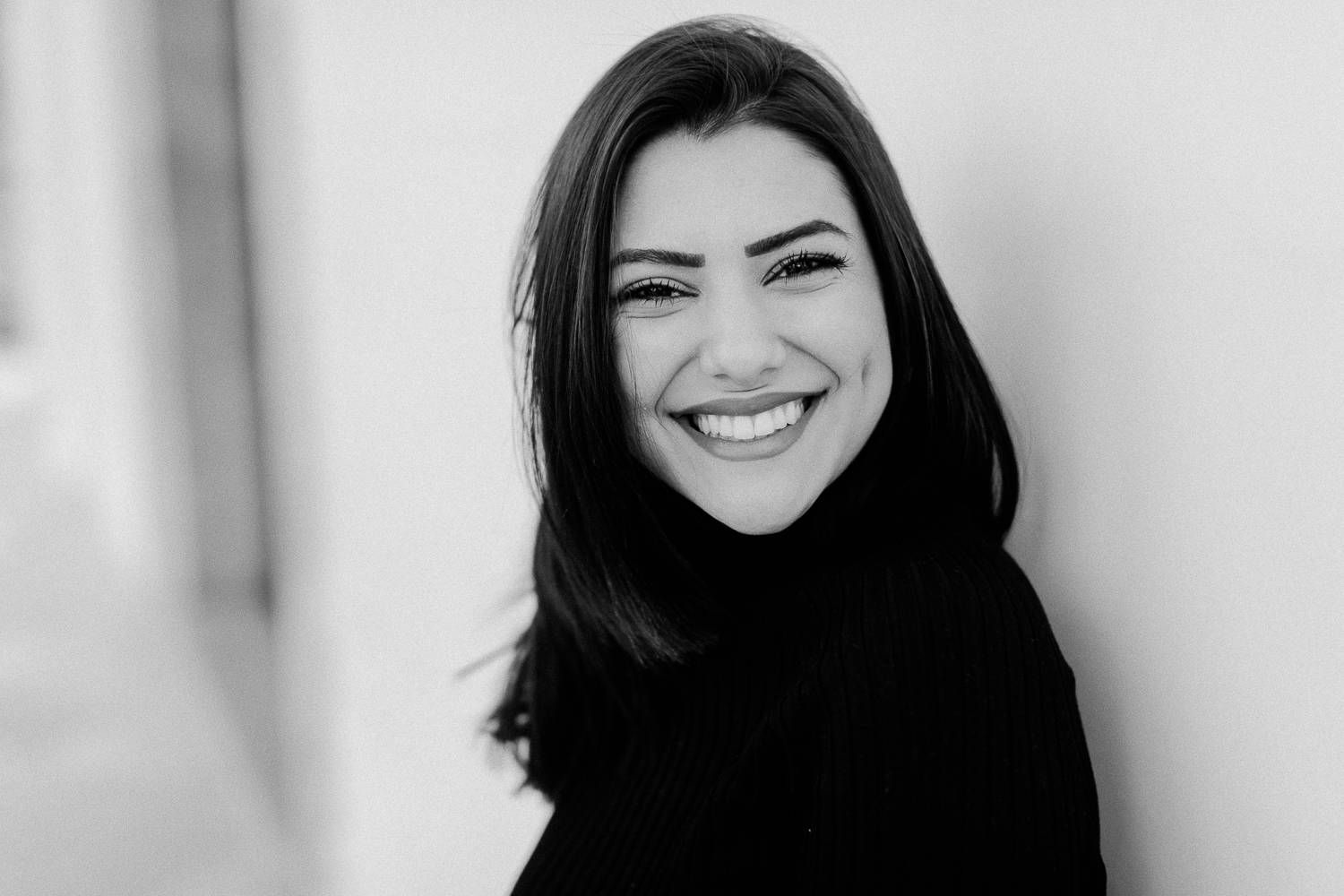 Black and white portrait of a smiling dark-haired woman in a black turtleneck.