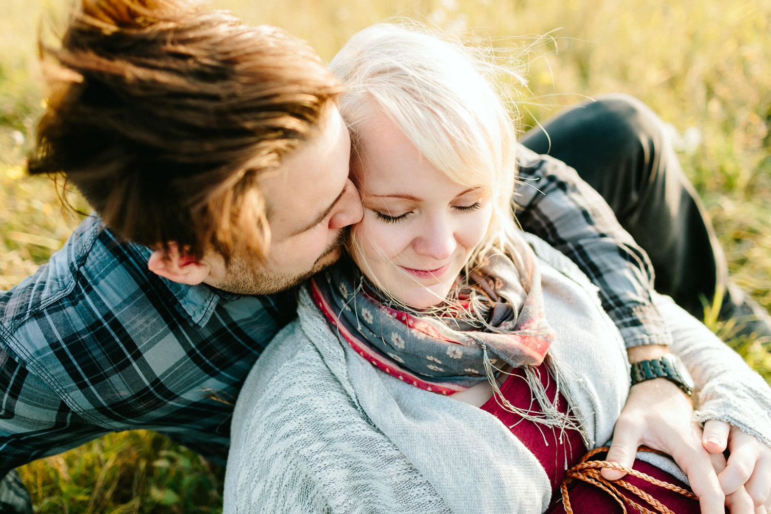 A couple cuddling closely together in a golden sunlit meadow during autumn.