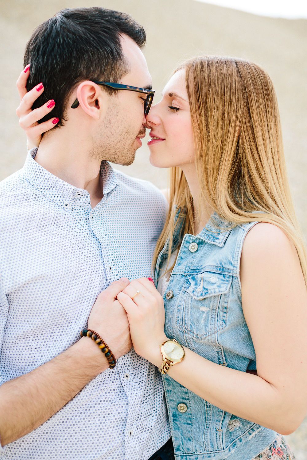 Close-up of couple about to kiss, woman holding mans shirt in warm sunlight.