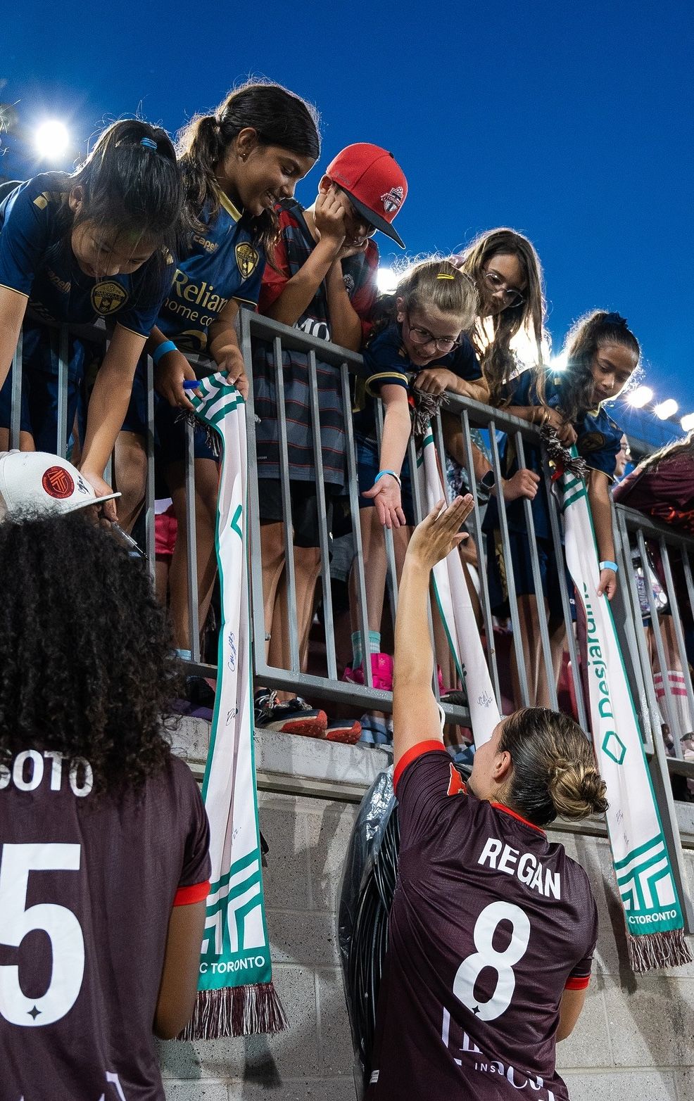 AFC Toronto players greet their youth fans giving high-fives and signing autographs after the end of a soccer match.