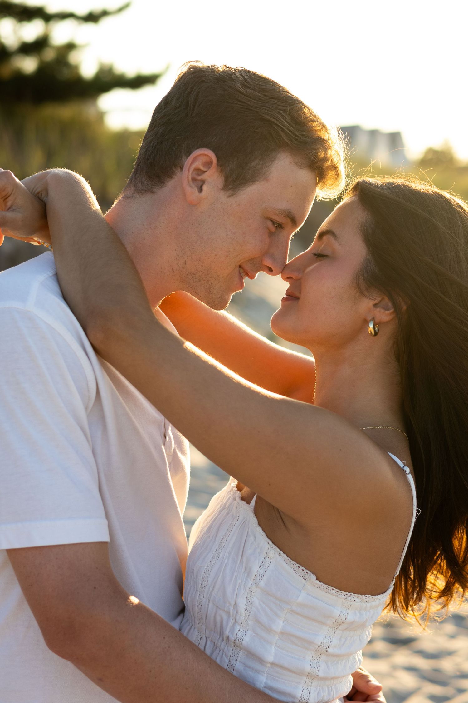 Romantic beach engagement photoshoot featuring couple in white clothing during golden hour in Lewes, Delaware.