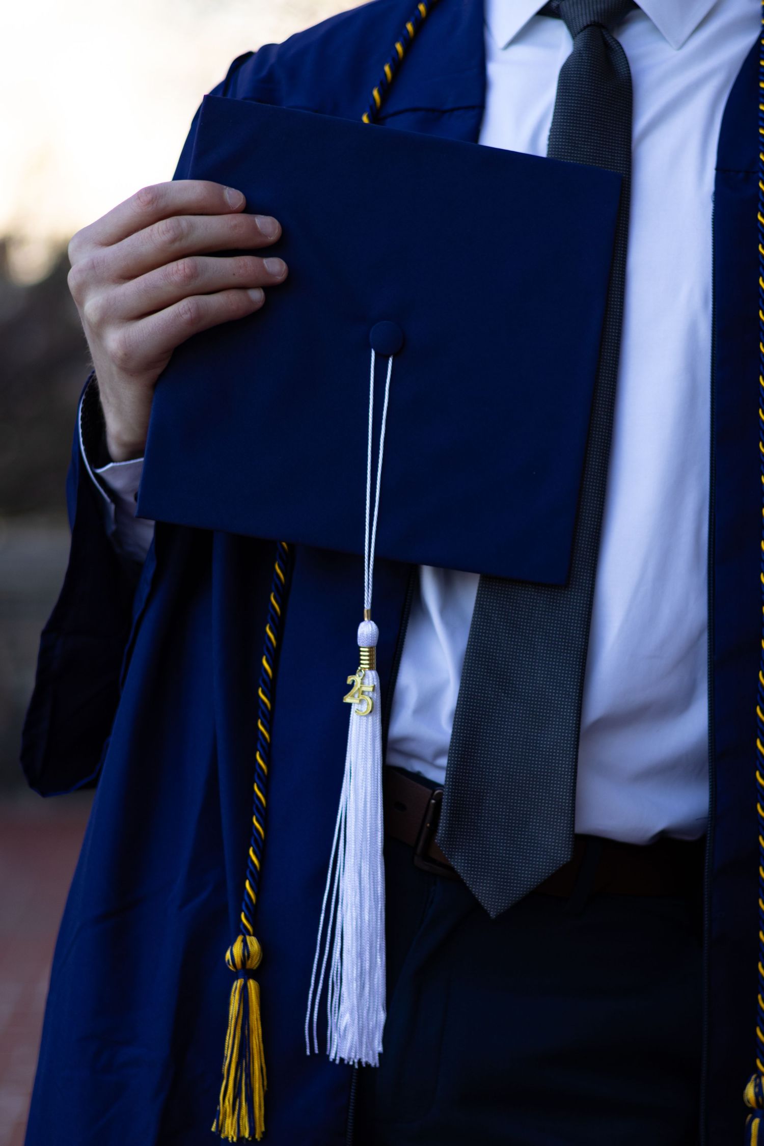 Close-up details of graduation regalia showing white tassel and navy blue gown at Penn State University.
